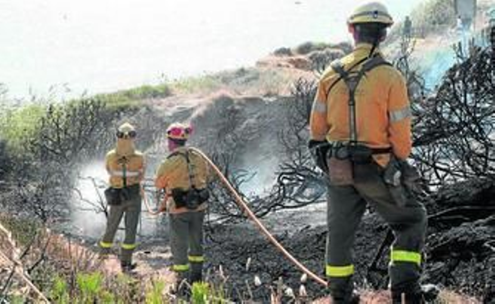 Tres efectivos del Infoca refrescan el terreno junto a la playa, ayer.