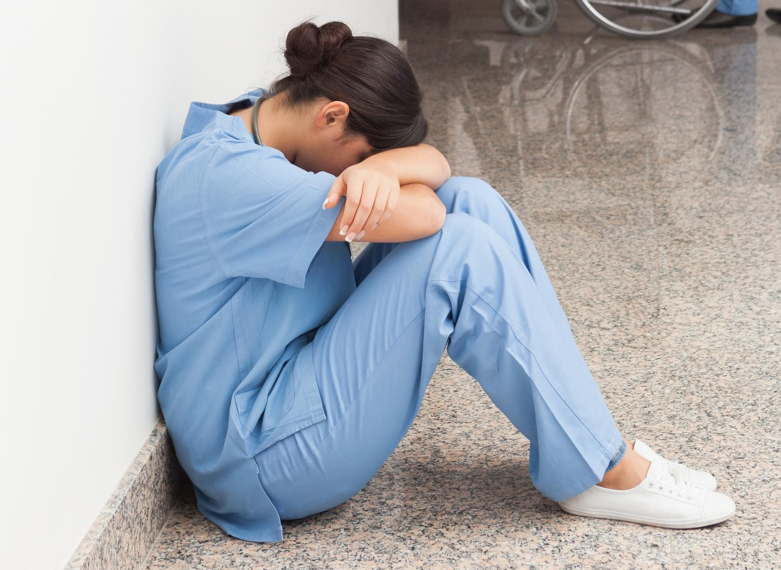 Una enfermera descansando en el suelo, exhausta tras la jornada laboral