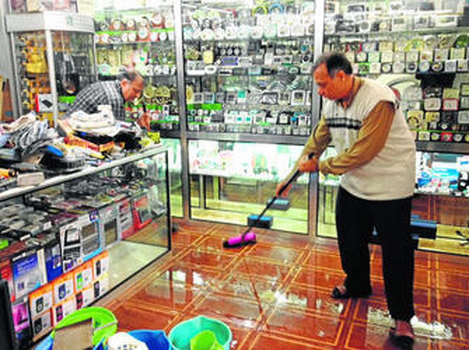 Basant Kumar Lalwani y un empleado arreglan su bazar fregona en mano.