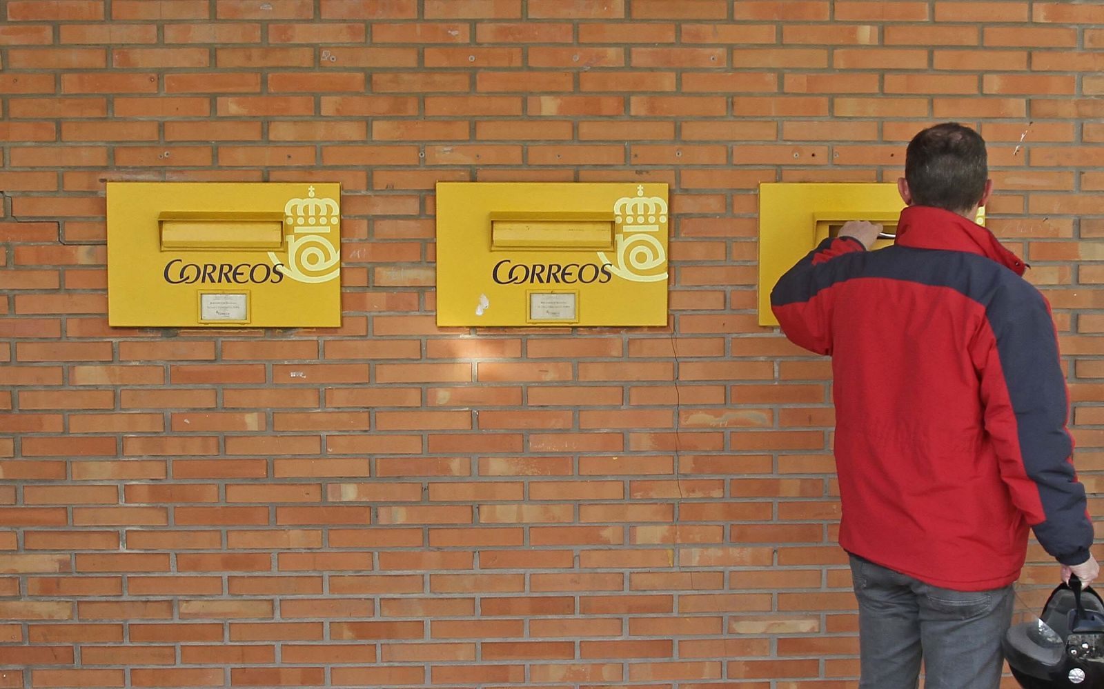 Un hombre deposita un envío en un buzón de la oficina de Ruiz Zorrilla en Algeciras