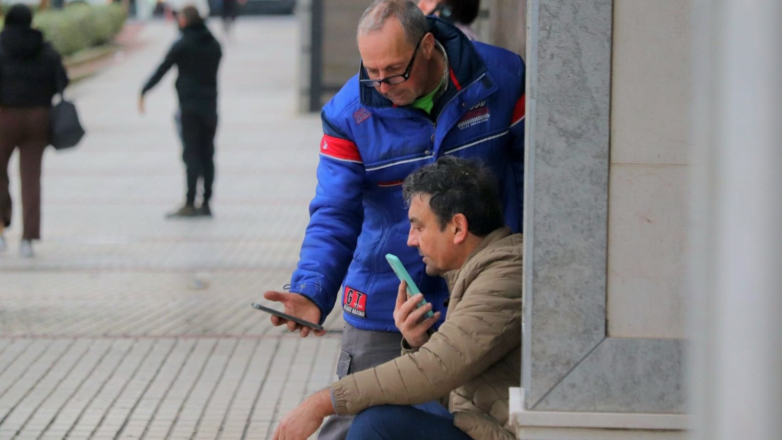 Vecinos desalojados pendientes del teléfono móvil a las afueras del hotel