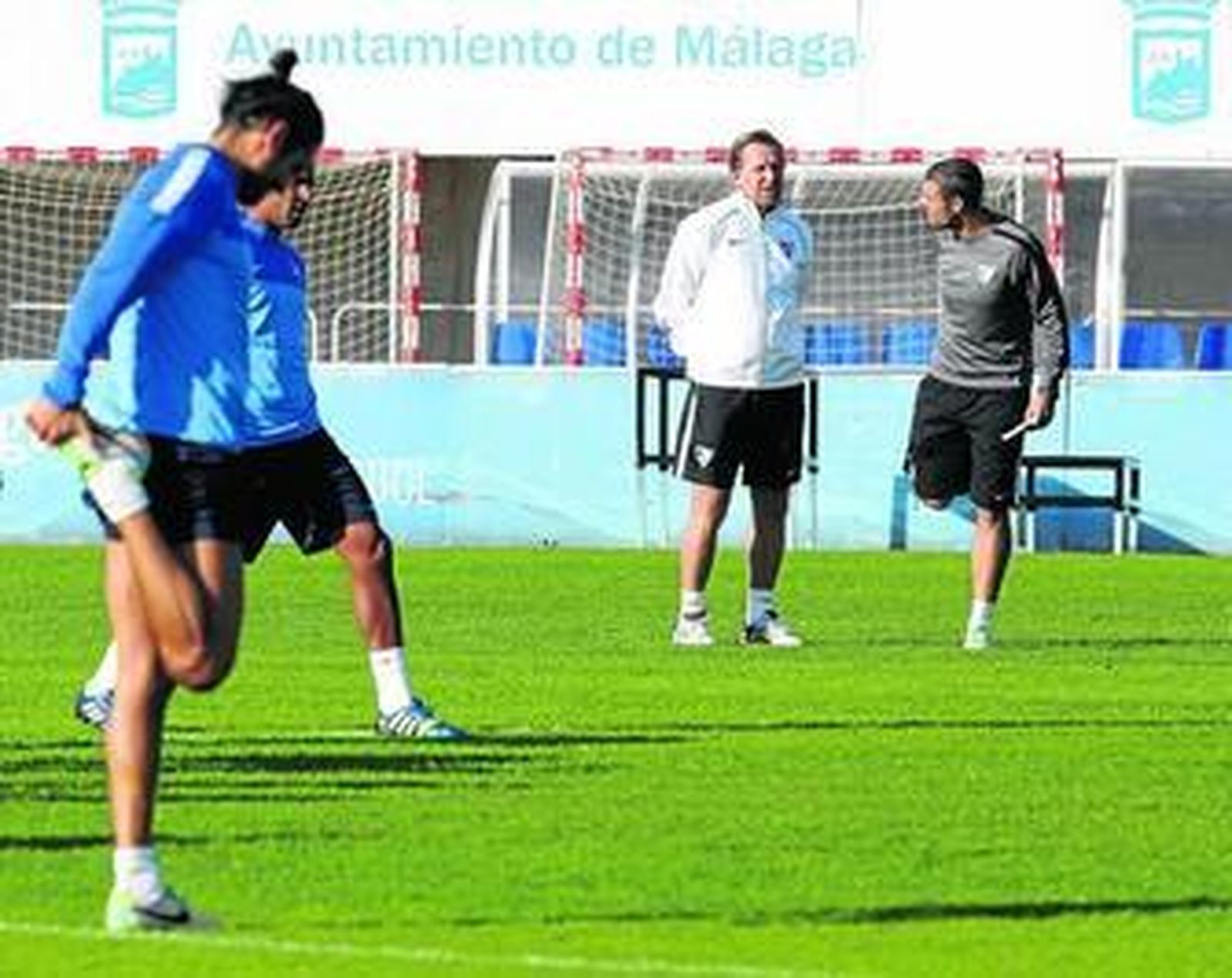 Schuster departe con Celestini mientras los jugadores cajistas realizan estiramientos.