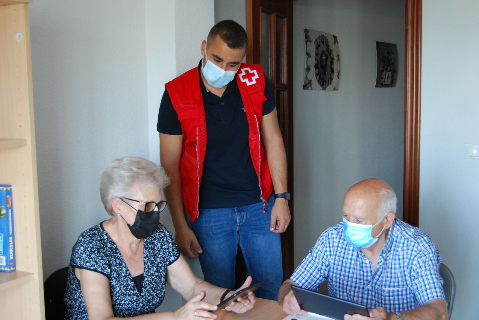 Voluntario de Cruz Roja ayuda a mayores con las nuevas tecnologías.