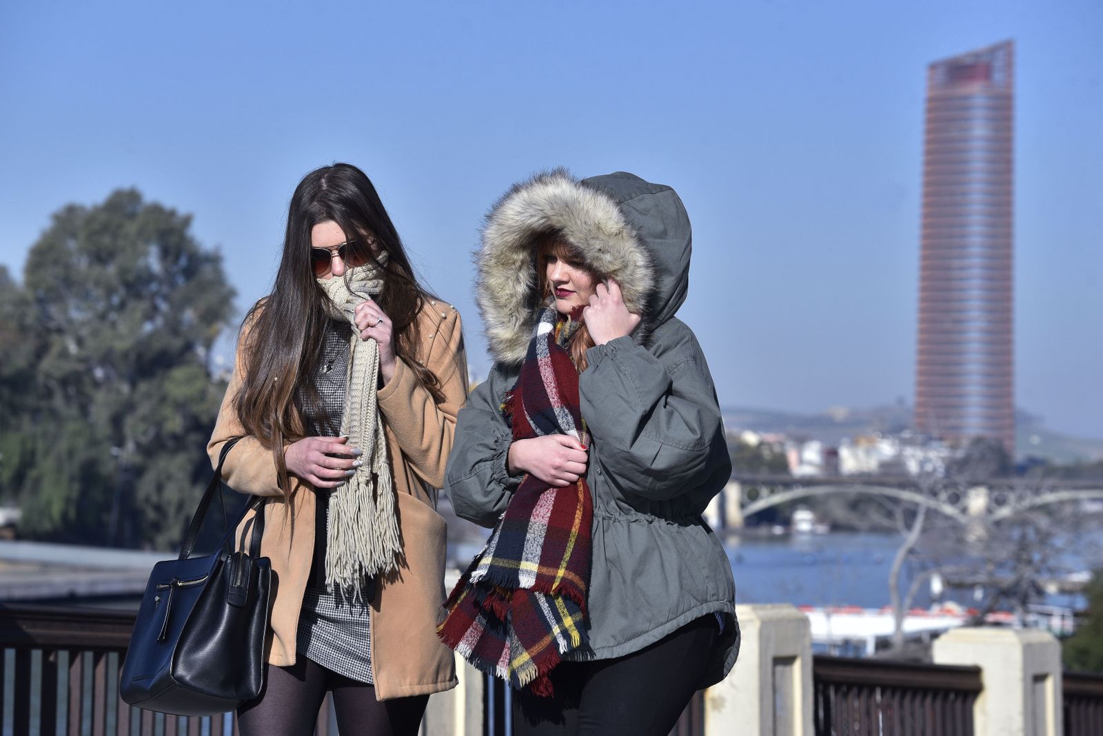 Dos jóvenes se protegen del frío en Sevilla.