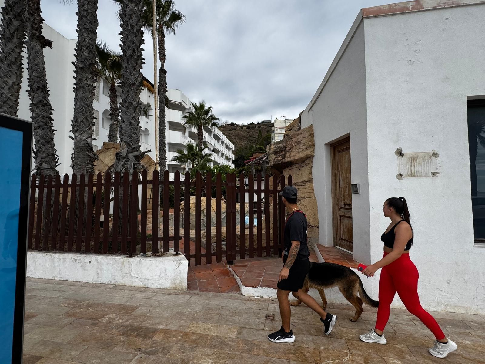 Dos jóvenes pasean junto al antiguo centro náutico de La Herradura