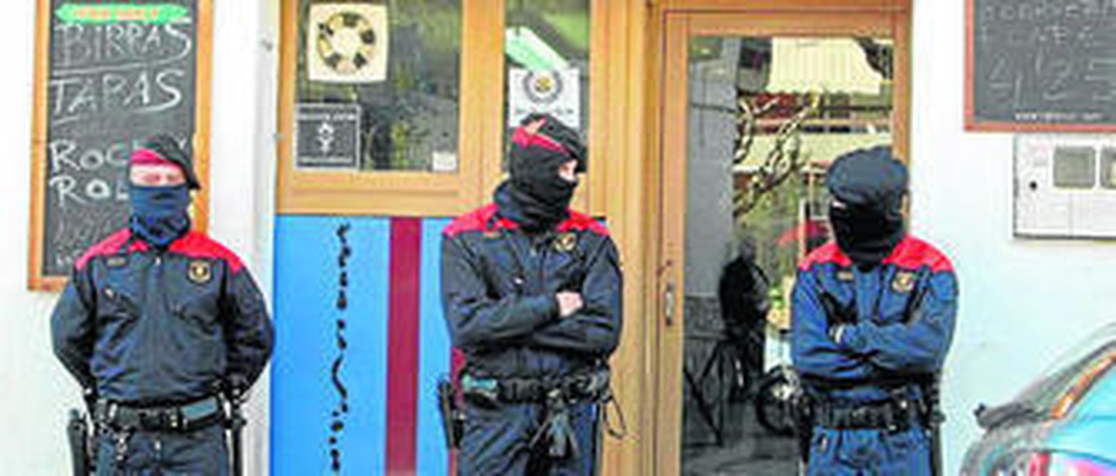 Tres 'mossos d'esquadra' custodian la puerta de un bar de Esparraguera (Barcelona). / ARCHIVO
