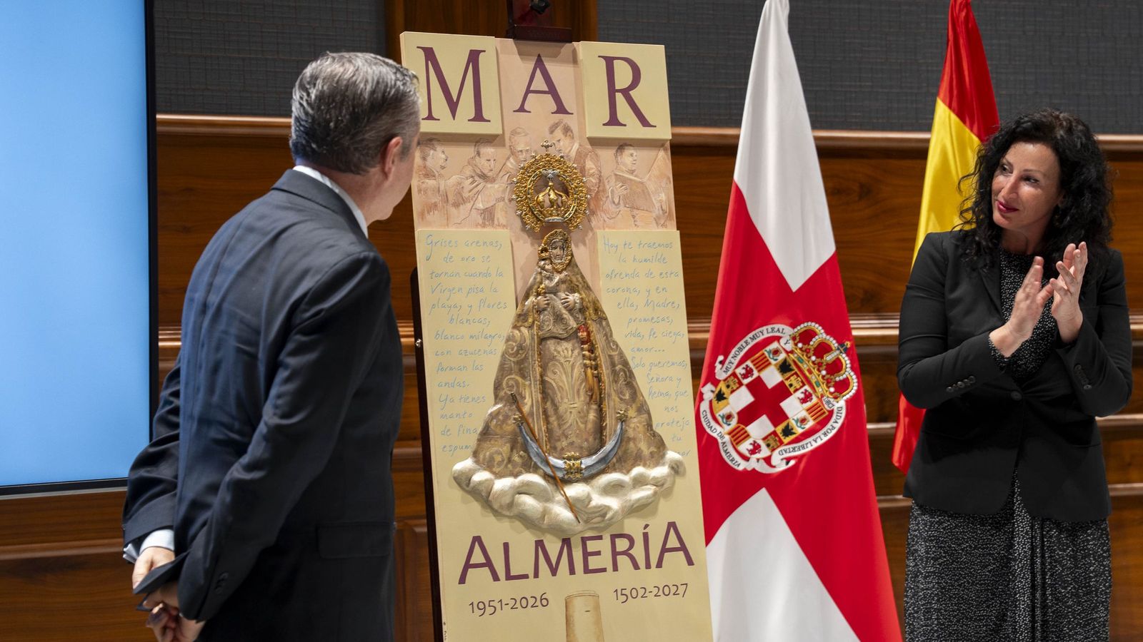 La alcaldesa de Almería, María del Mar Váquez, observa el cartel de la Virgen del Mar.