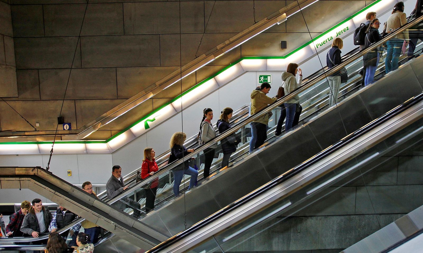 Viajeros subiendo por la escalera mecánica de la estación subterránea Puerta de Jerez.