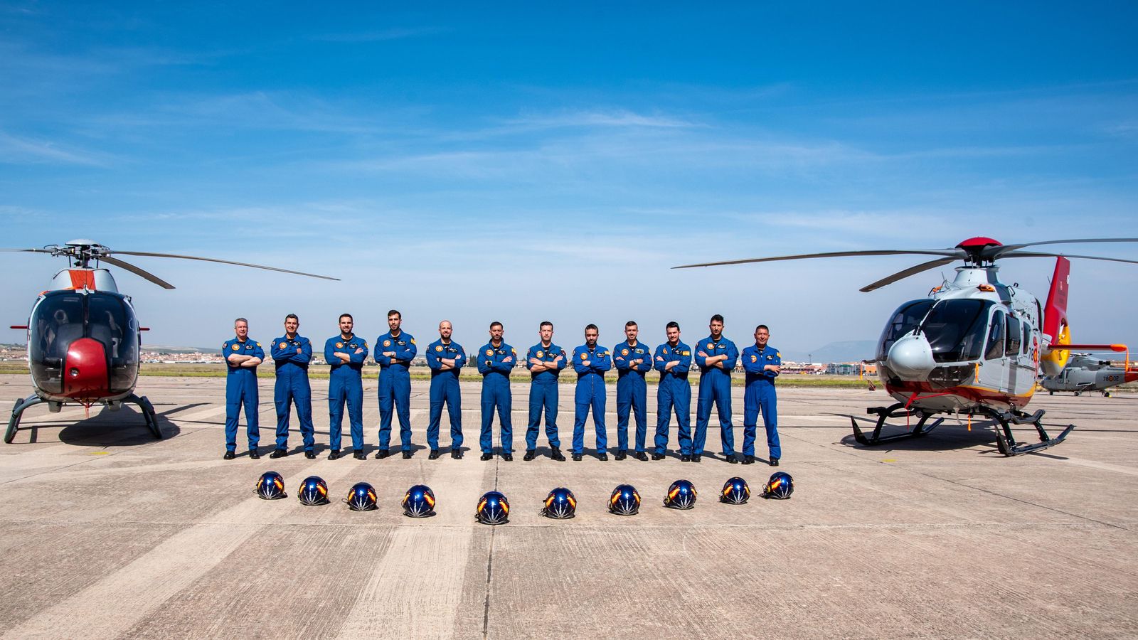 Los pilotos de la Patrulla Aspa posan junto a dos vehículos.