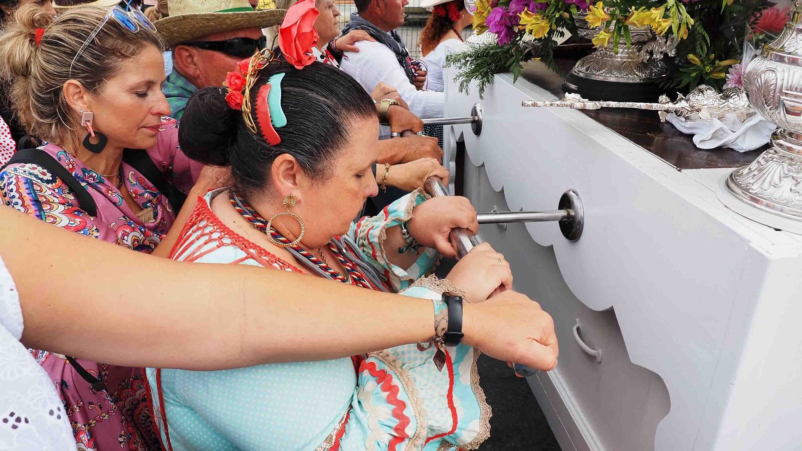 Varios peregrinos cartayeros caminan agarrados a la carreta del Simpecado