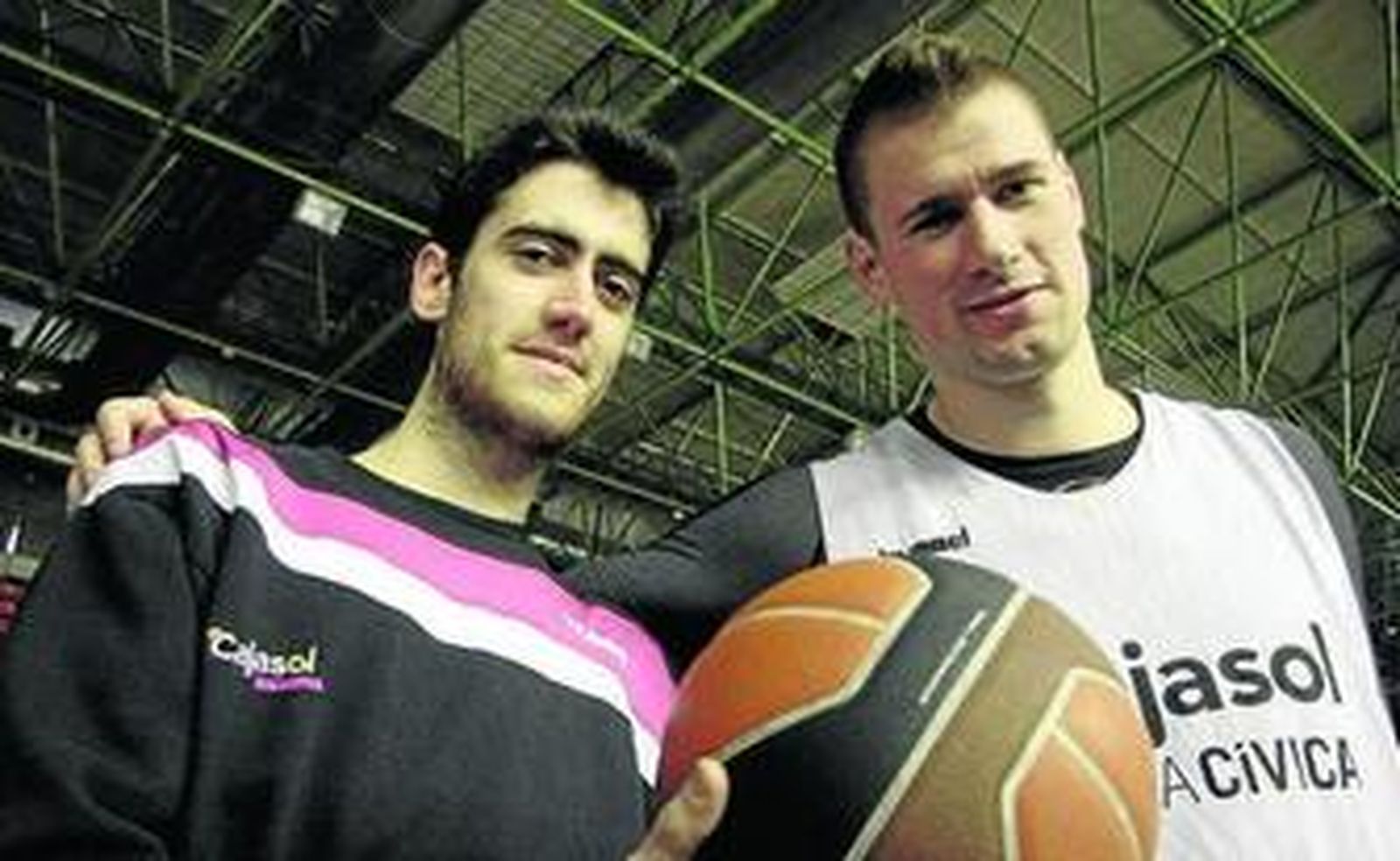 Sastre sostiene un balón y Davis le pasa la mano por el hombro.