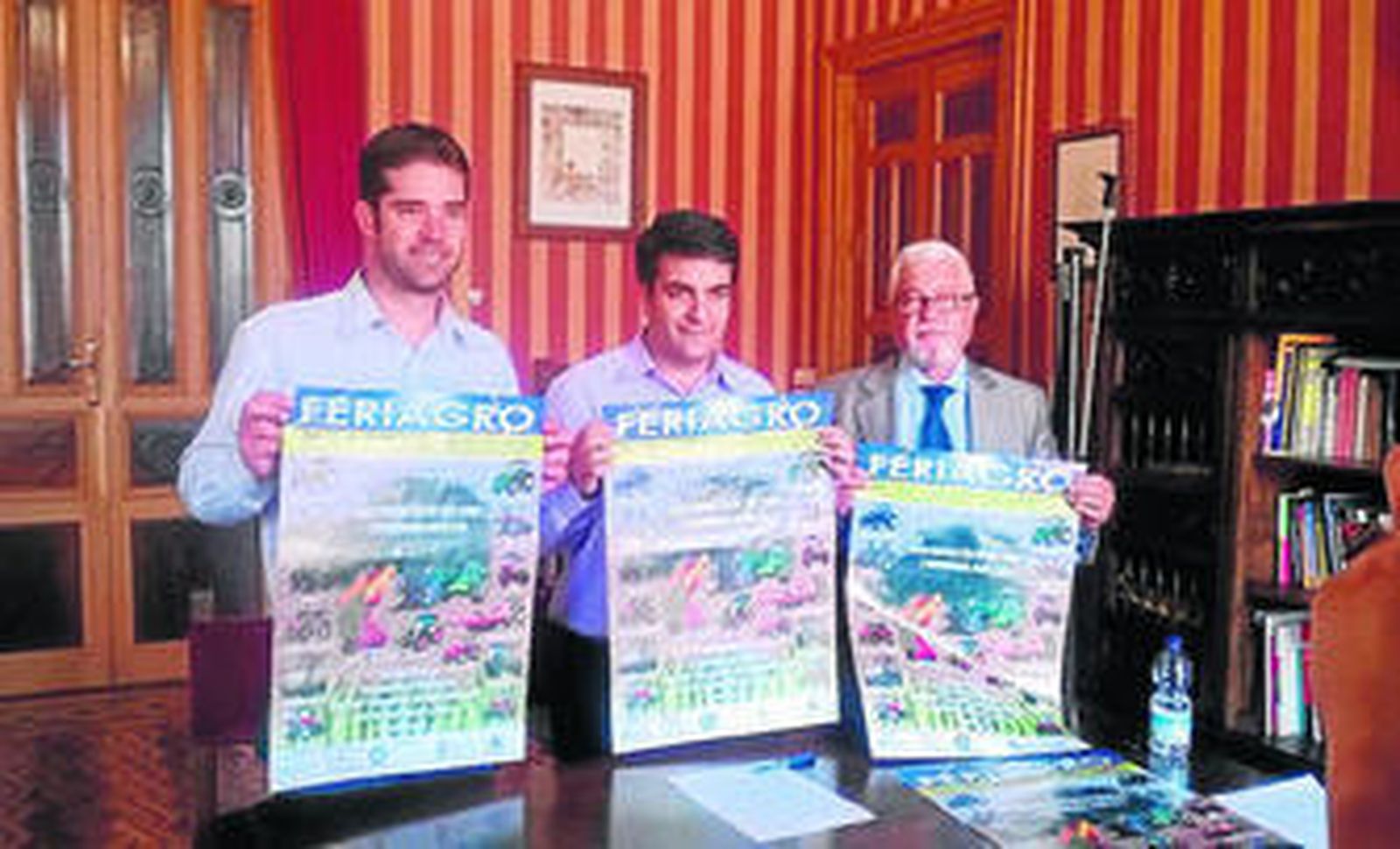 Algunos de los organizadores de la feria posan con el cartel anunciador.