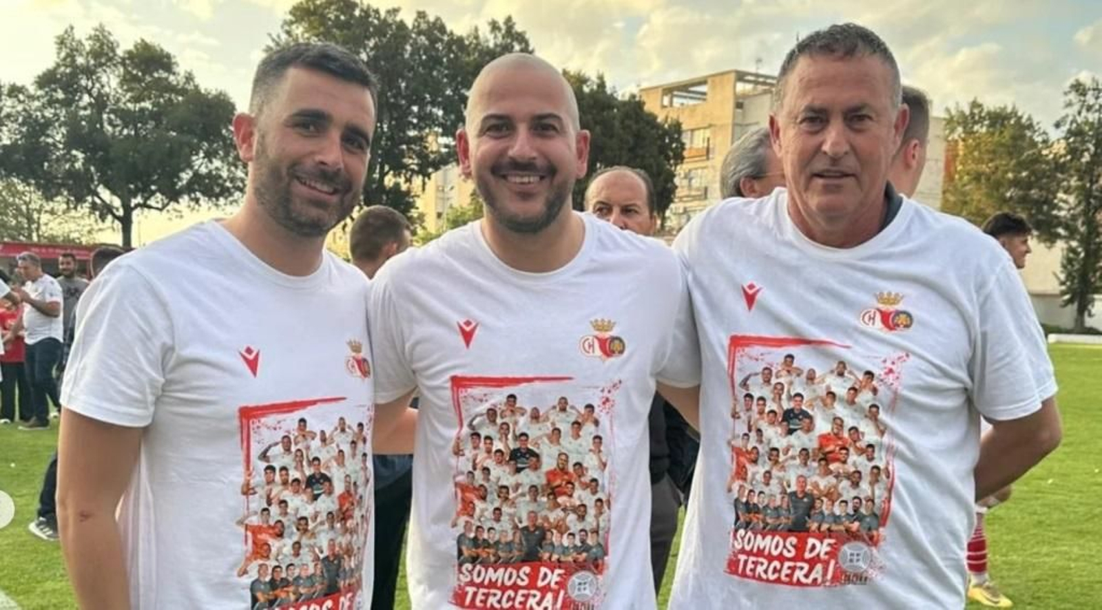 Alfonso Cortijo (d) y Javi Jiménez escoltan a Diego Ramírez en la celebración del ascenso a Tercera Federación.