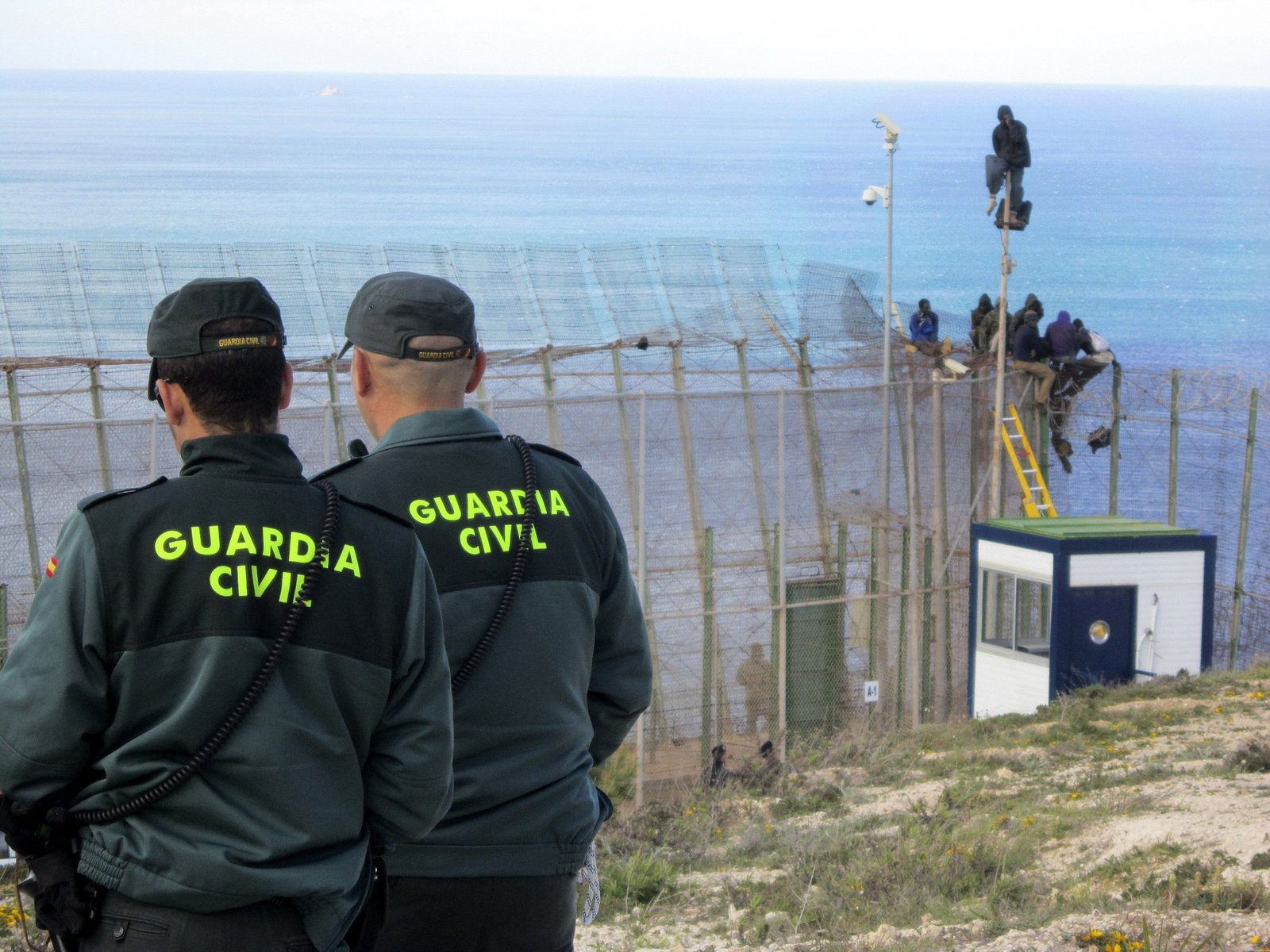 Dos agentes de la Guardia Civil observan cómo saltan la valla de Melilla varios subsaharianos en abril de 2014.