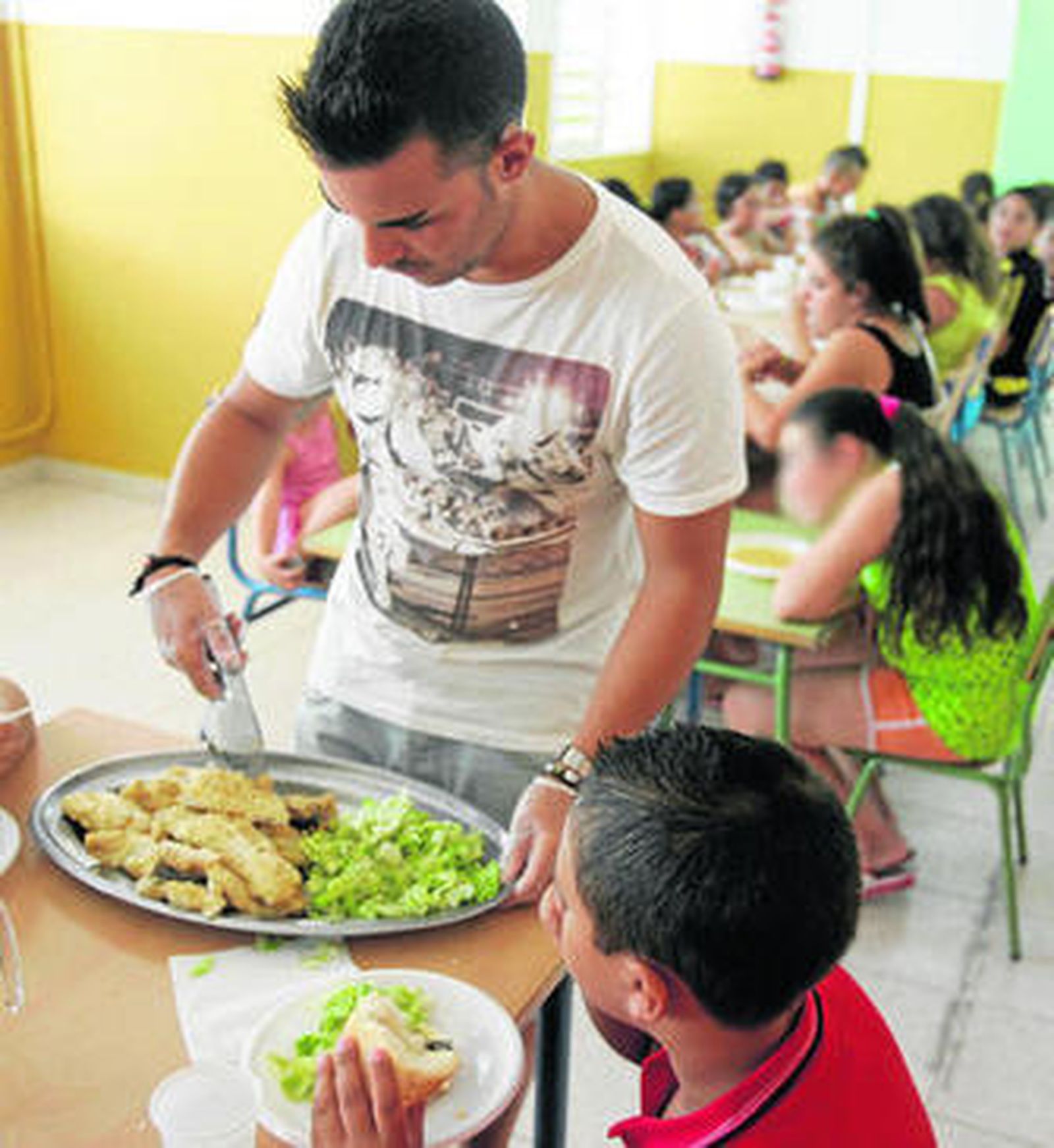 Un monitor de comedor escolar sirve a uno de los comensales.
