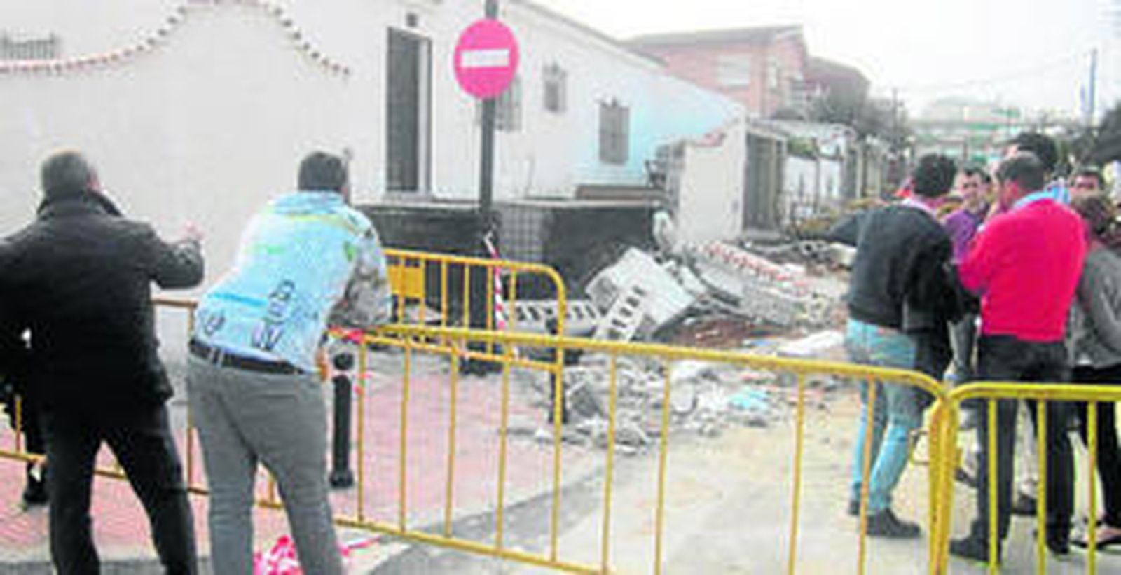 Varios vecinos miran el estado en el que quedó la calle tras el derrumbe del muro.
