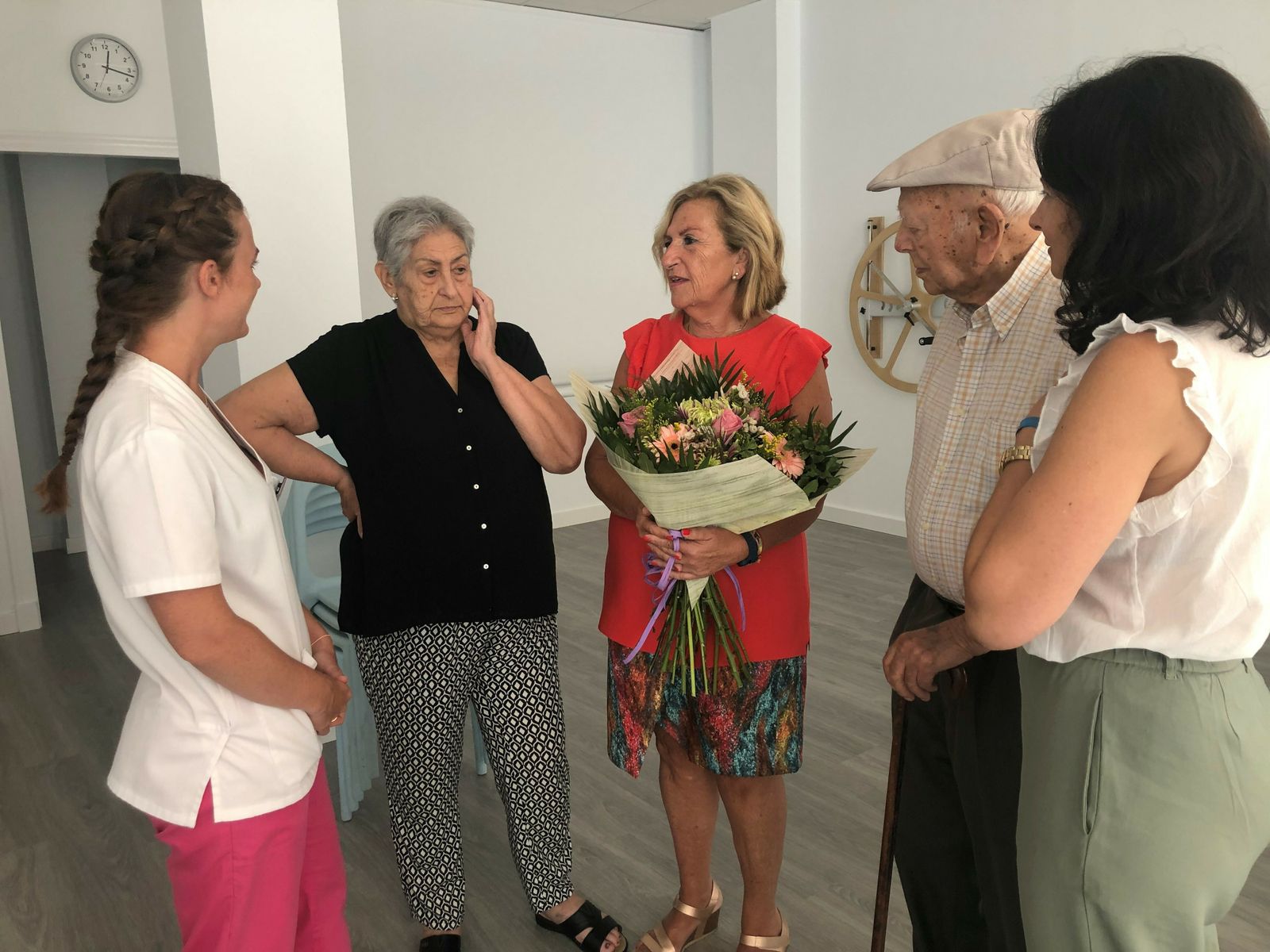 Imagen de Carmen Lara junto a Milagros Ruiz Berciano (gerente), Vanessa Ruiz Berciano (directora) y dos usuarios durante su vista al centro de estancia diurna San Juan.