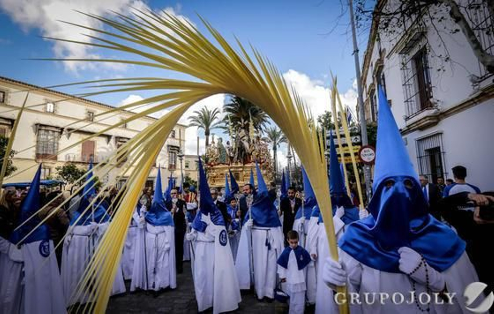 El paso de misterio de la Entrada Triunfal de la Hermandad de la Estrella se dirige hacia el palquillo la Carrera Oficial rodeado de palmas y cofrades blancos y azules.

Foto: Miguel Ángel González