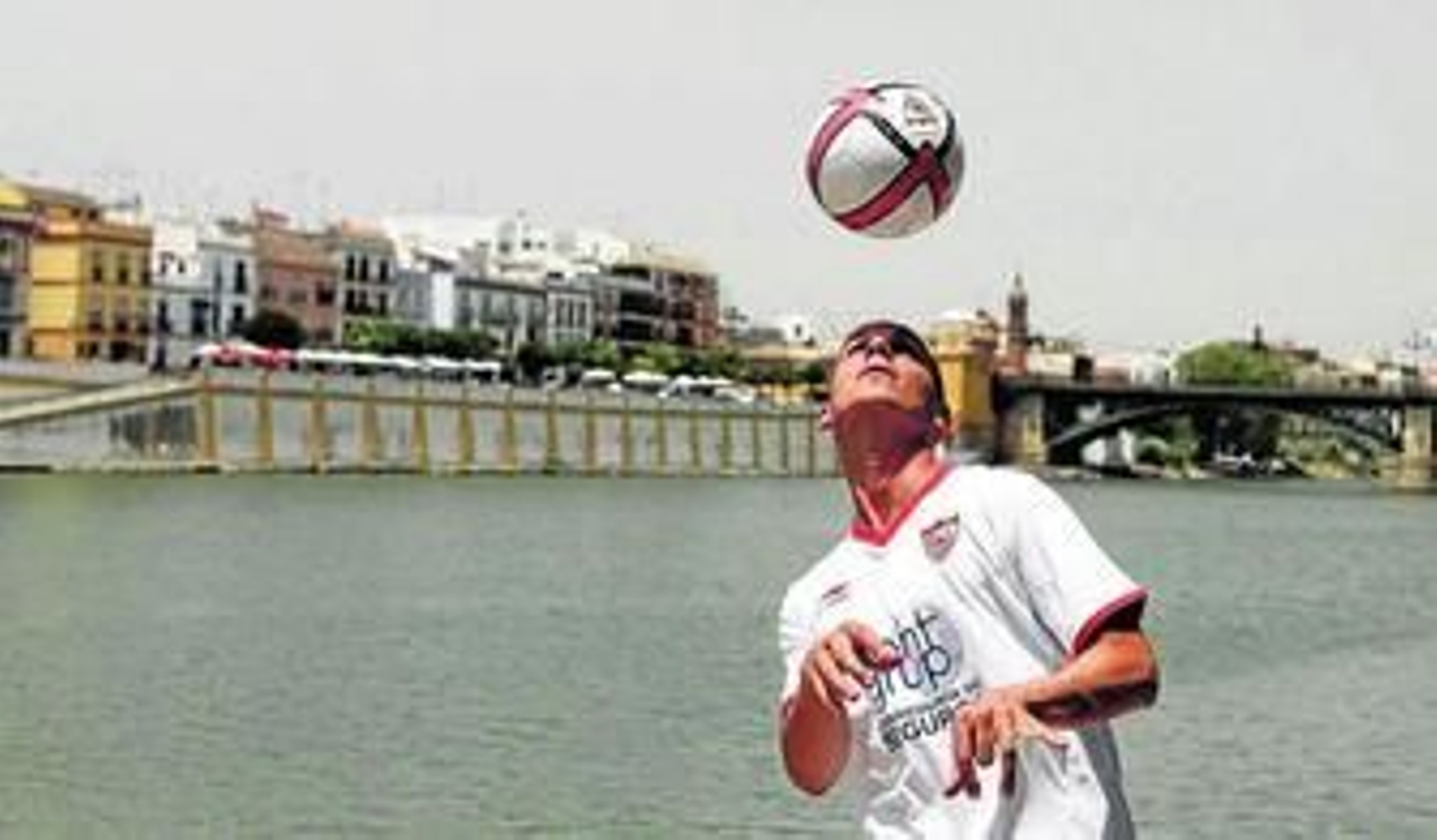 Javi Hervás juguetea con el balón con el río Guadalquivir y Triana al fondo.