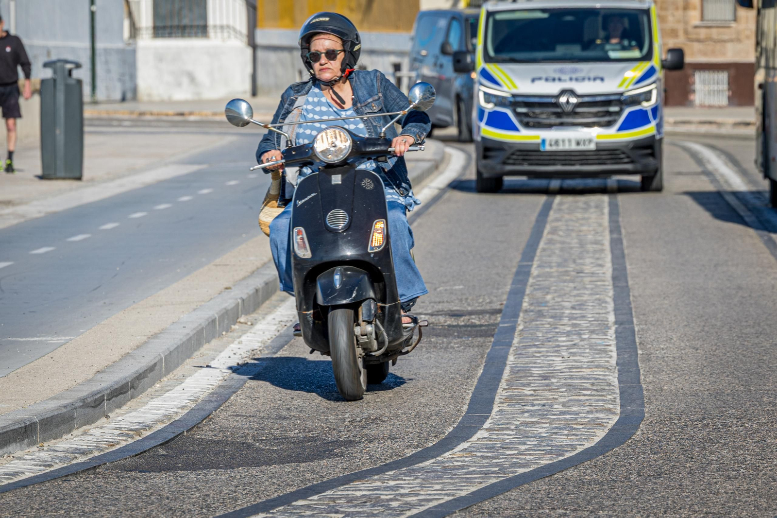 Una ciudadana conduce con precaución por la zona, repleta de baches.