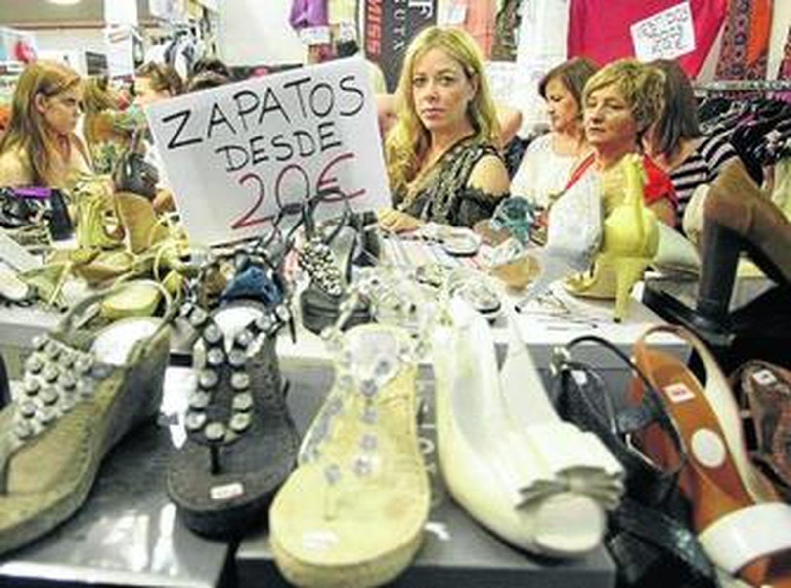 Varias mujeres miran los zapatos con descuentos expuestos a la venta en la feria outlet de Los Barrios.