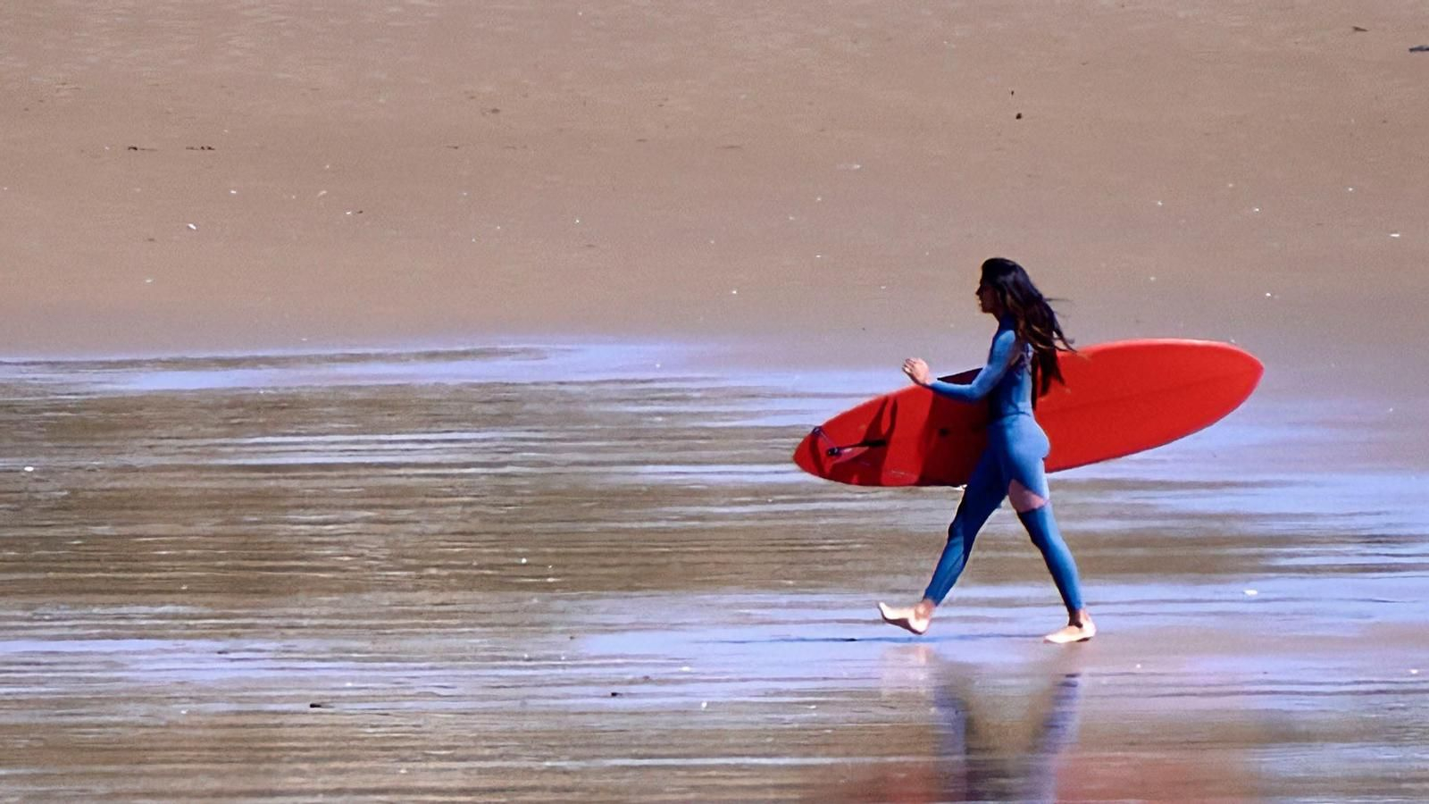 Una mujer se dirige al agua para practicar surf
