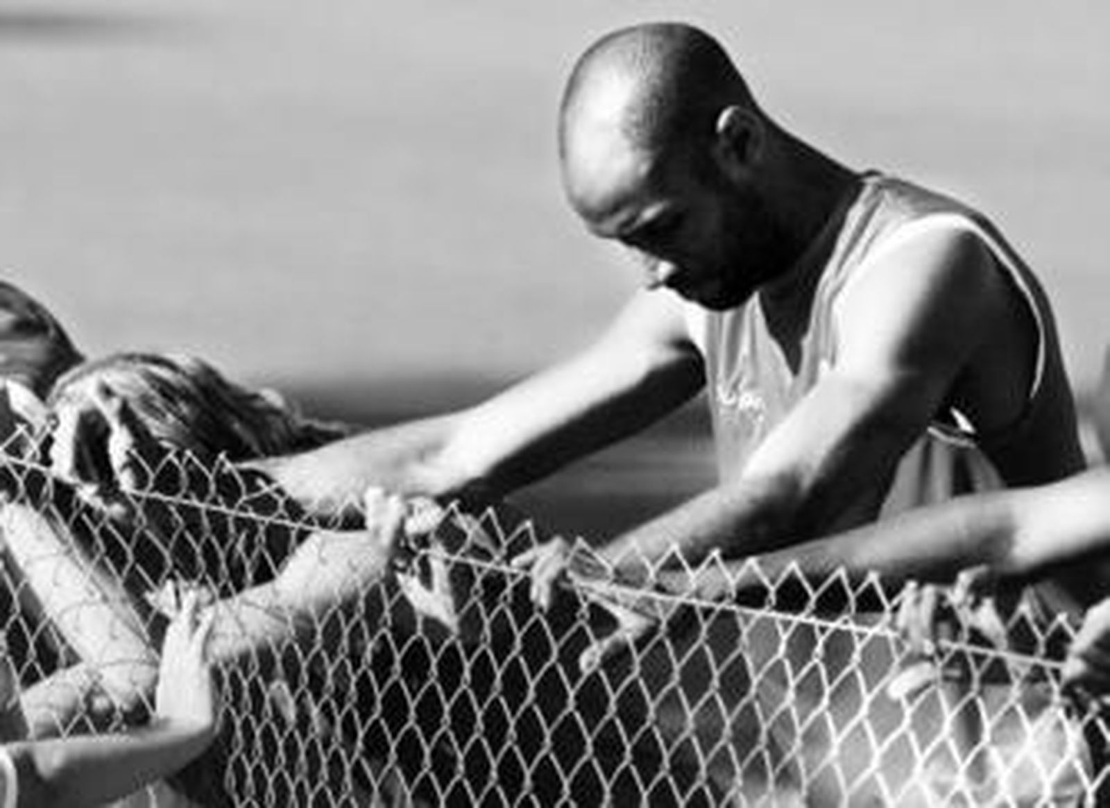 Kanoute realiza ejercicios de estiramientos apoyado en la valla de uno de los campos de la ciudad deportiva.