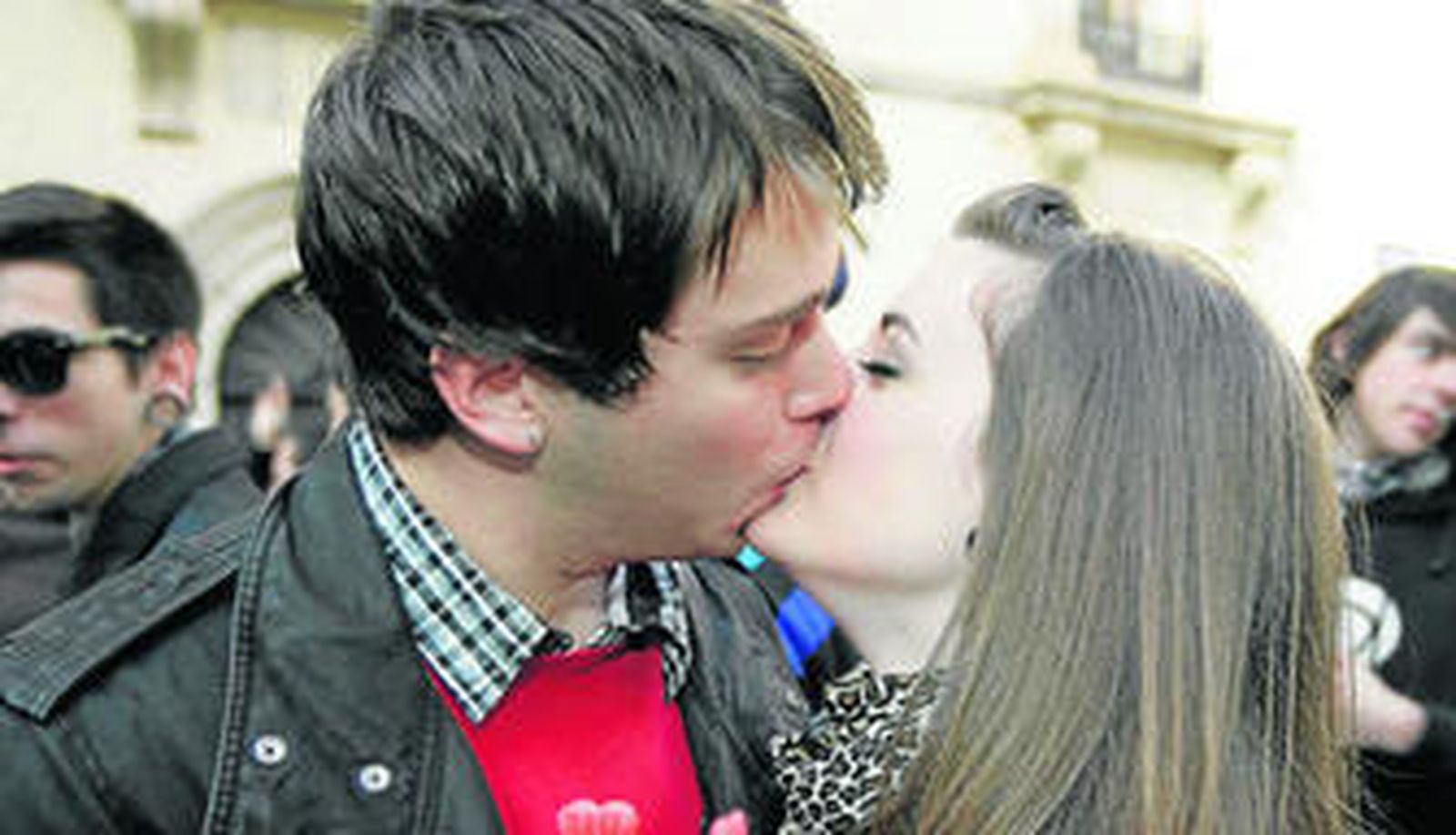 Una pareja de enamorados se besa en la calle.