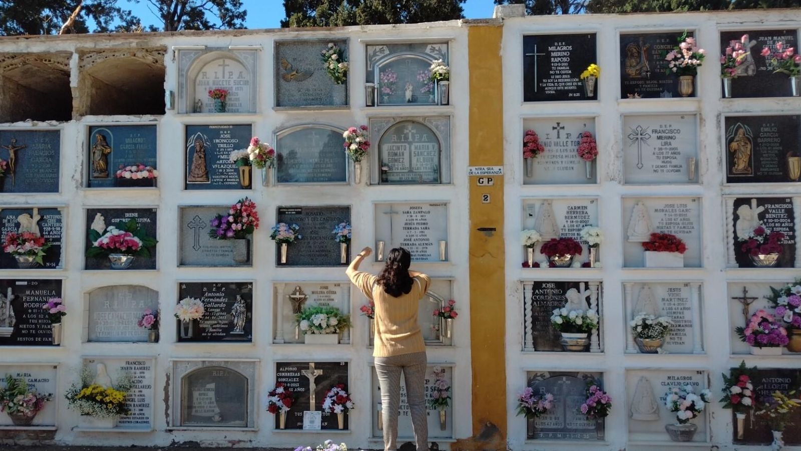 Una mujer coloca exornos delante de los nichos.