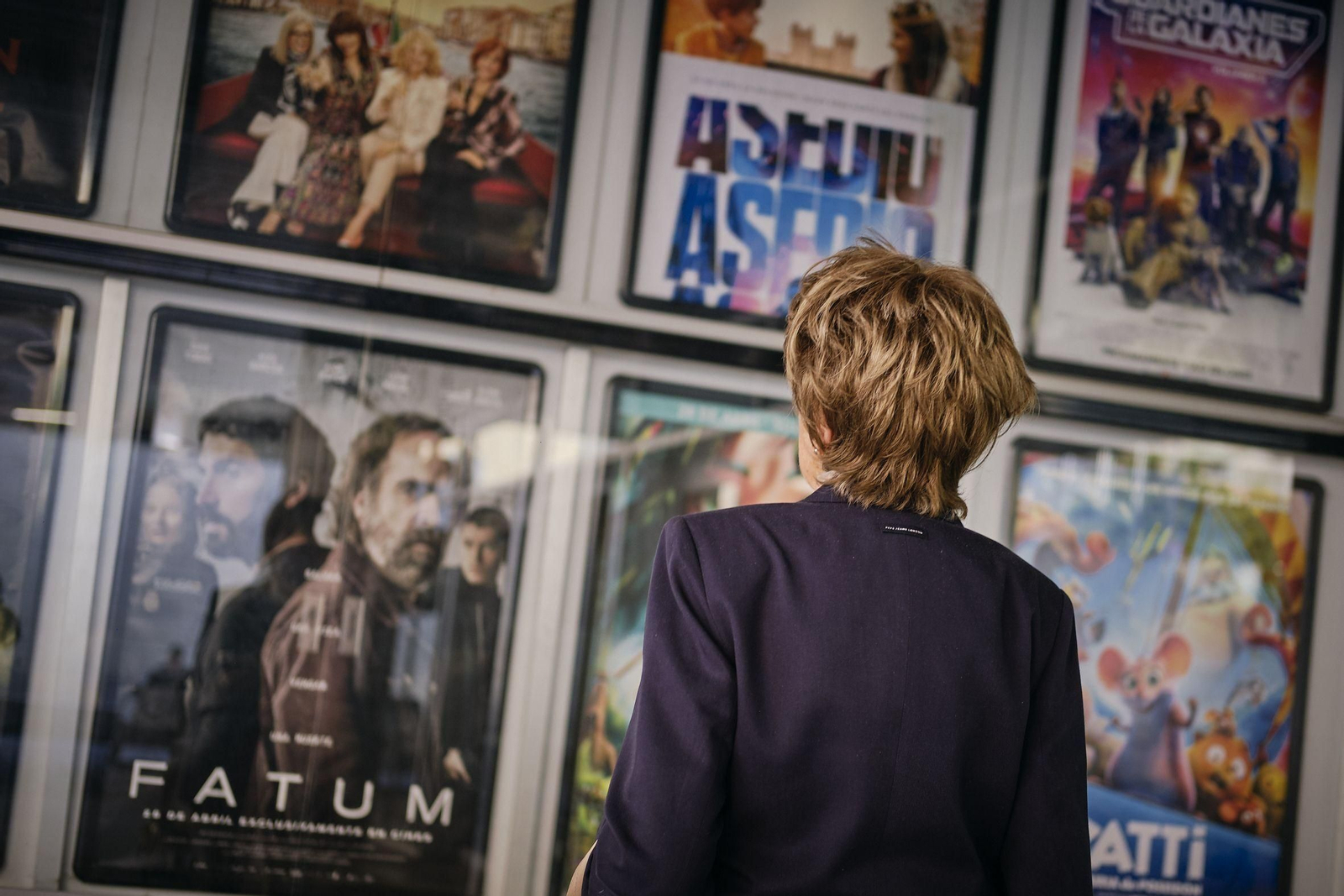 Una mujer mira una cartelera de cine