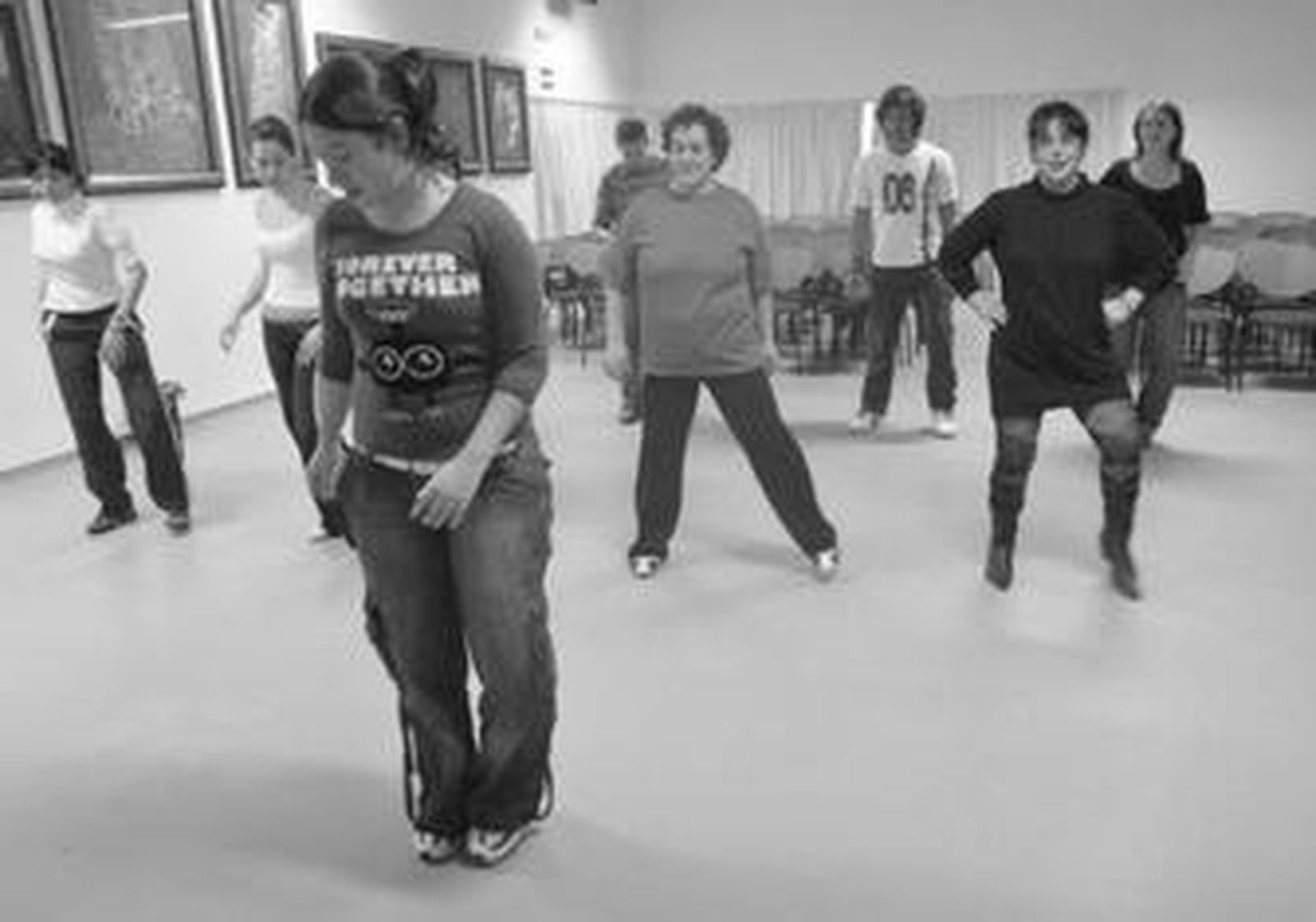La monitora enseña pasos de baile a alumnos de taller de bailes latinos de la Casa de la Juventud.