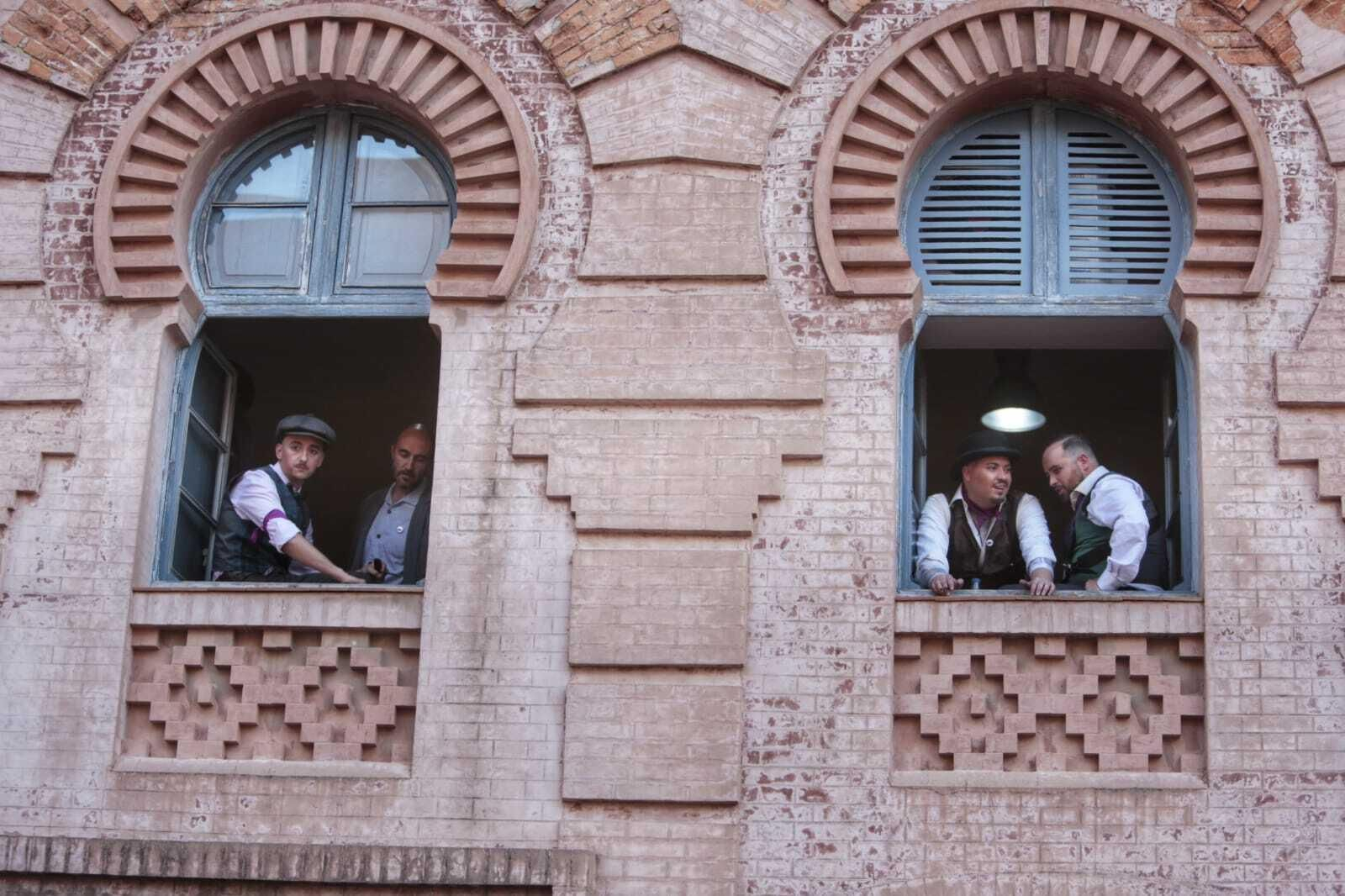 Componentes de la comparsa 'El club de los ignorantes' , aplena luz del día, , asomados a una de las ventanas del teatro