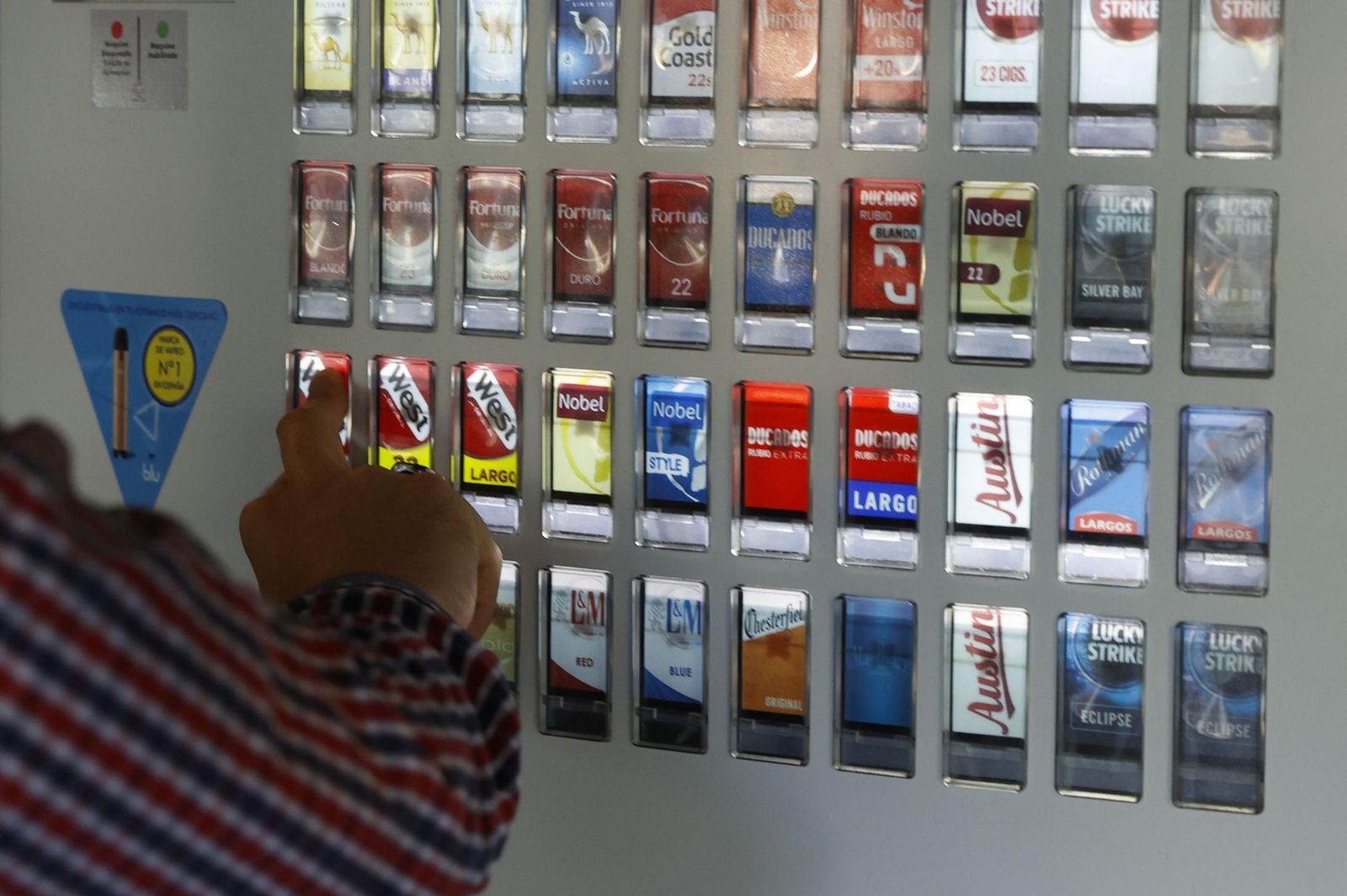 Un hombre compra una cajetilla de tabaco en una máquina expendedora.