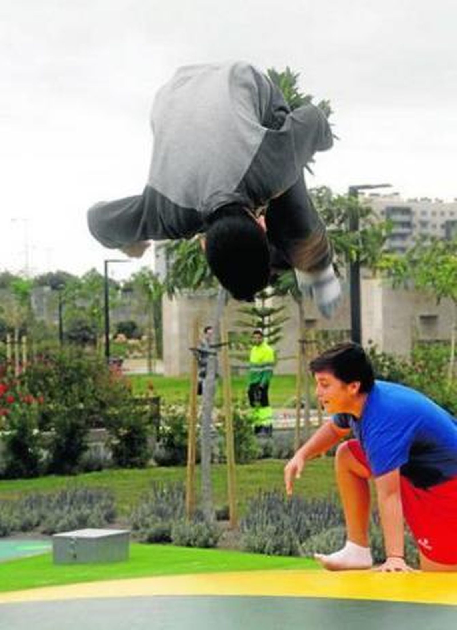 Un niño hace una voltereta sobre la colchoneta del parque.