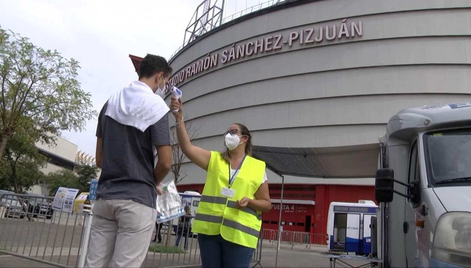 Una sanitaria toma la temperatura a un aficionado antes de someterse al test PCR.
