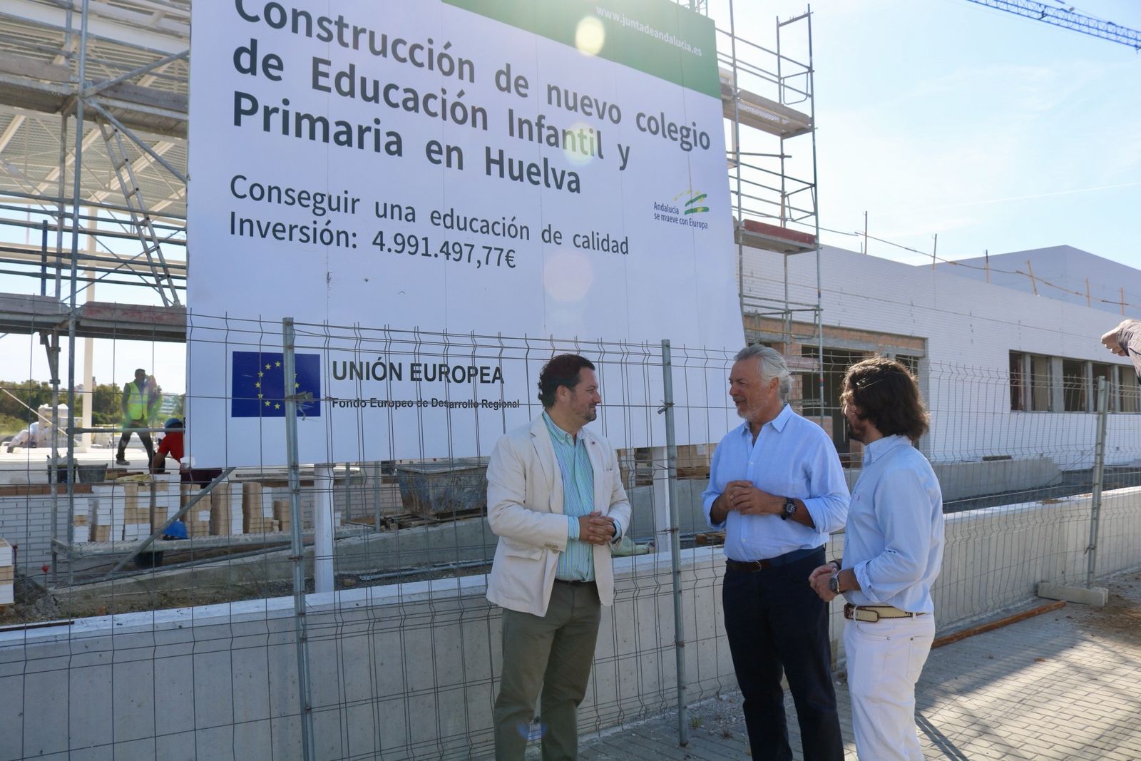 Los populares ante el cartel anunciador de la obra del colegio del Ensanche.