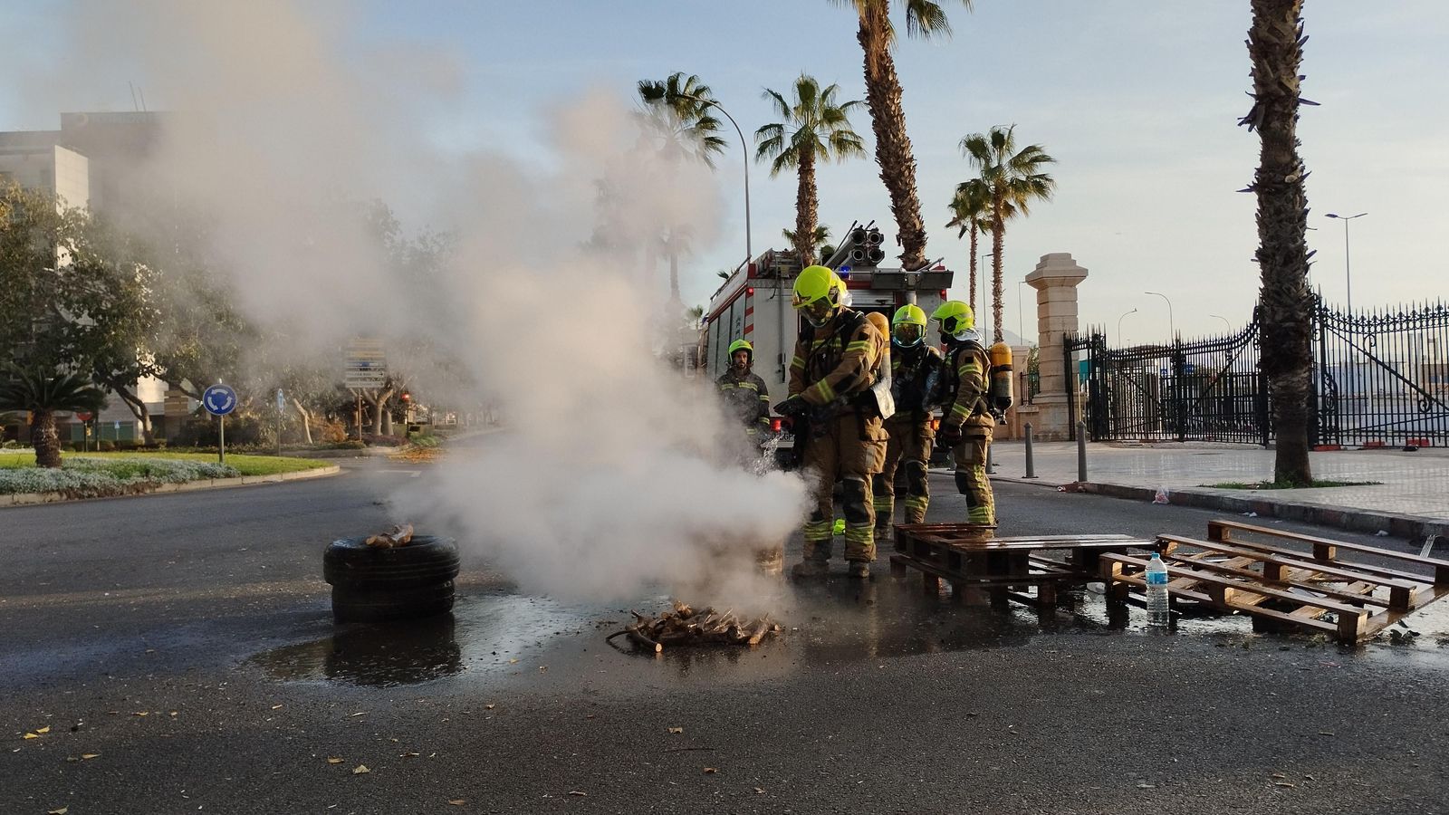 Bomberos apagan rescoldos del fuego que los manifestantes hicieron para calentarse durante la noche.