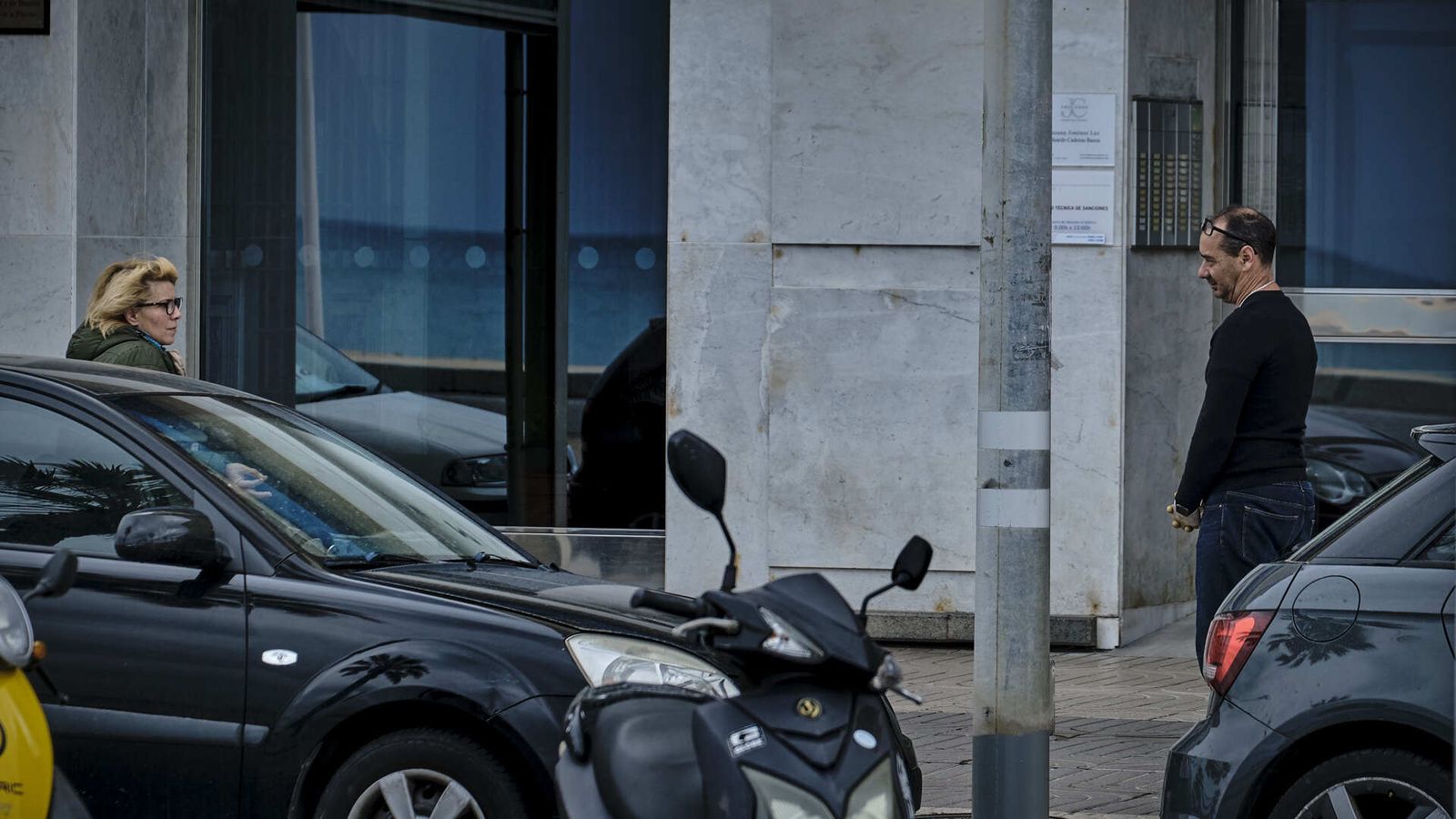 Dos personas conversan a gran distancia en un portal del edificio Reina Victoria