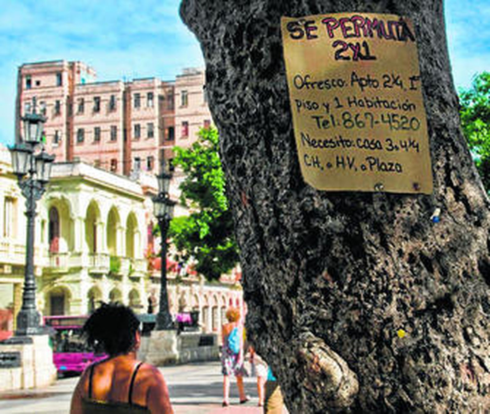 Una mujer observa un cartel para intercambiar viviendas colgado en un árbol de un parque de La Habana.