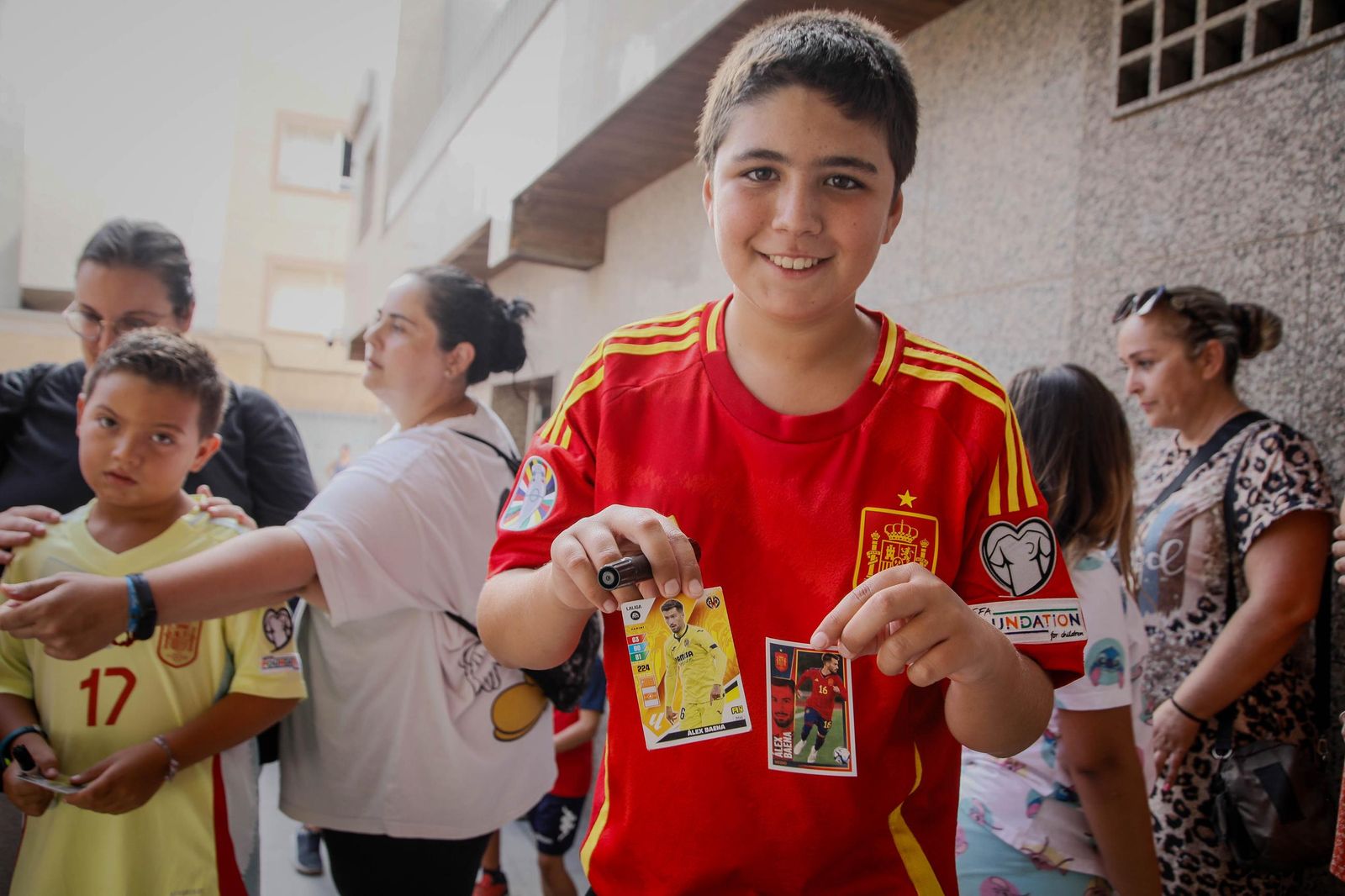 Un niño posa con dos cromos preparados para que se los firmase el reciente campeón olímpico y de la Eurocopa.