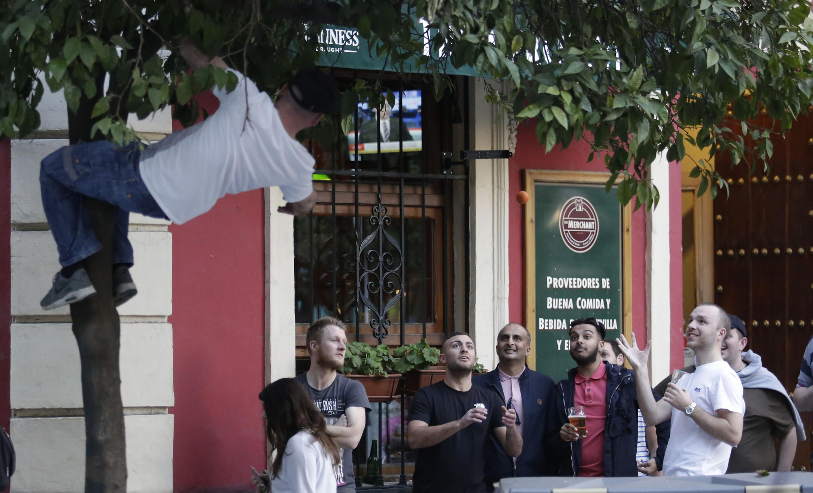Un aficionado del Manchester United lanza una naranja a sus acompañantes en la puerta del pub Merchant.