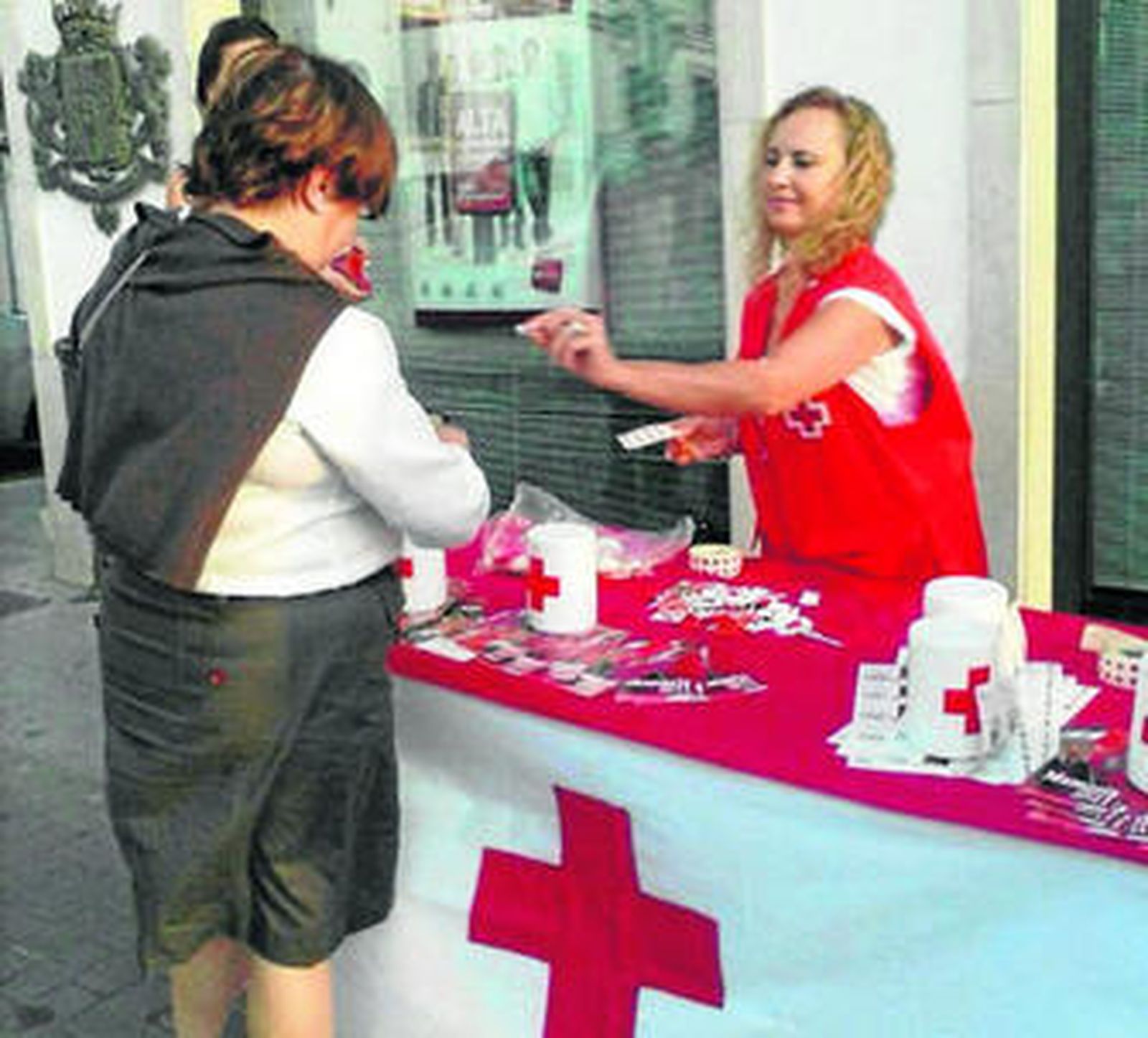 Una voluntaria coloca una pegatina a una mujer por su donativo durante la colecta del Día de la Banderita.