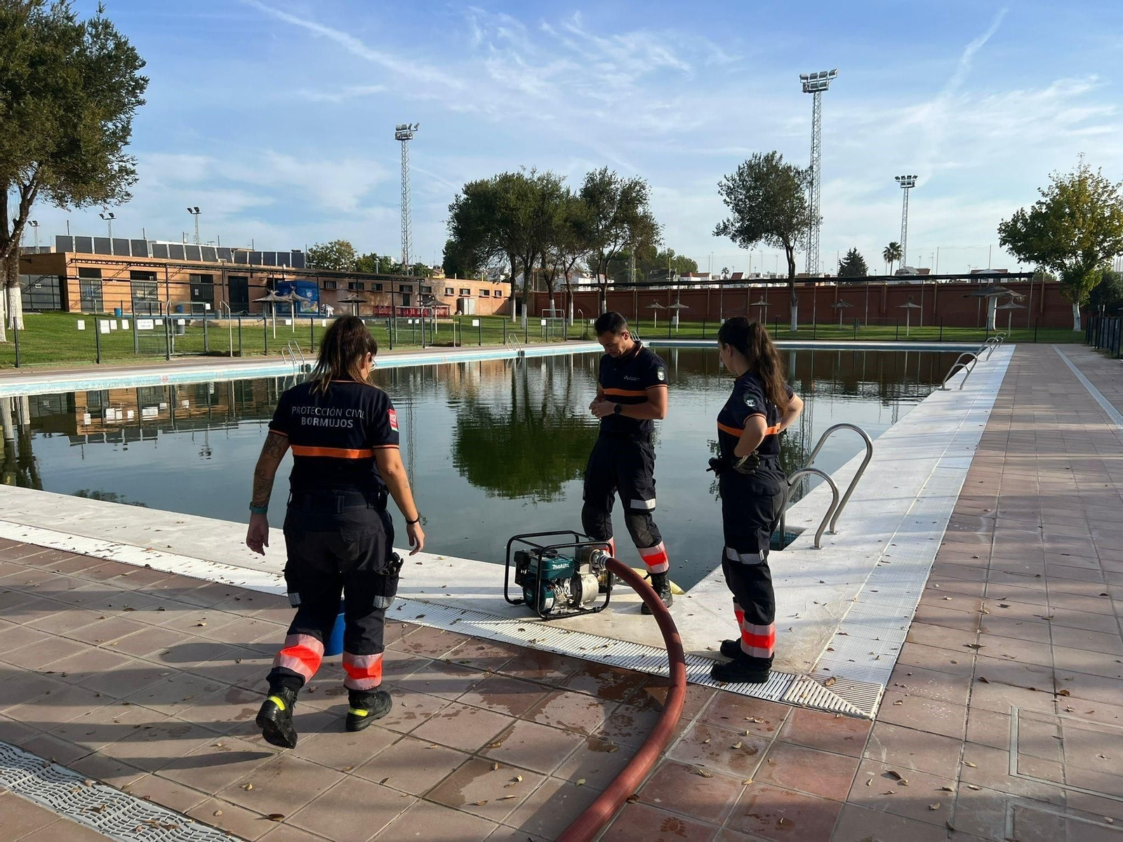 Voluntarios de Protección Civil manipulan la bomba de extracción para llenar los camiones de baldeo.