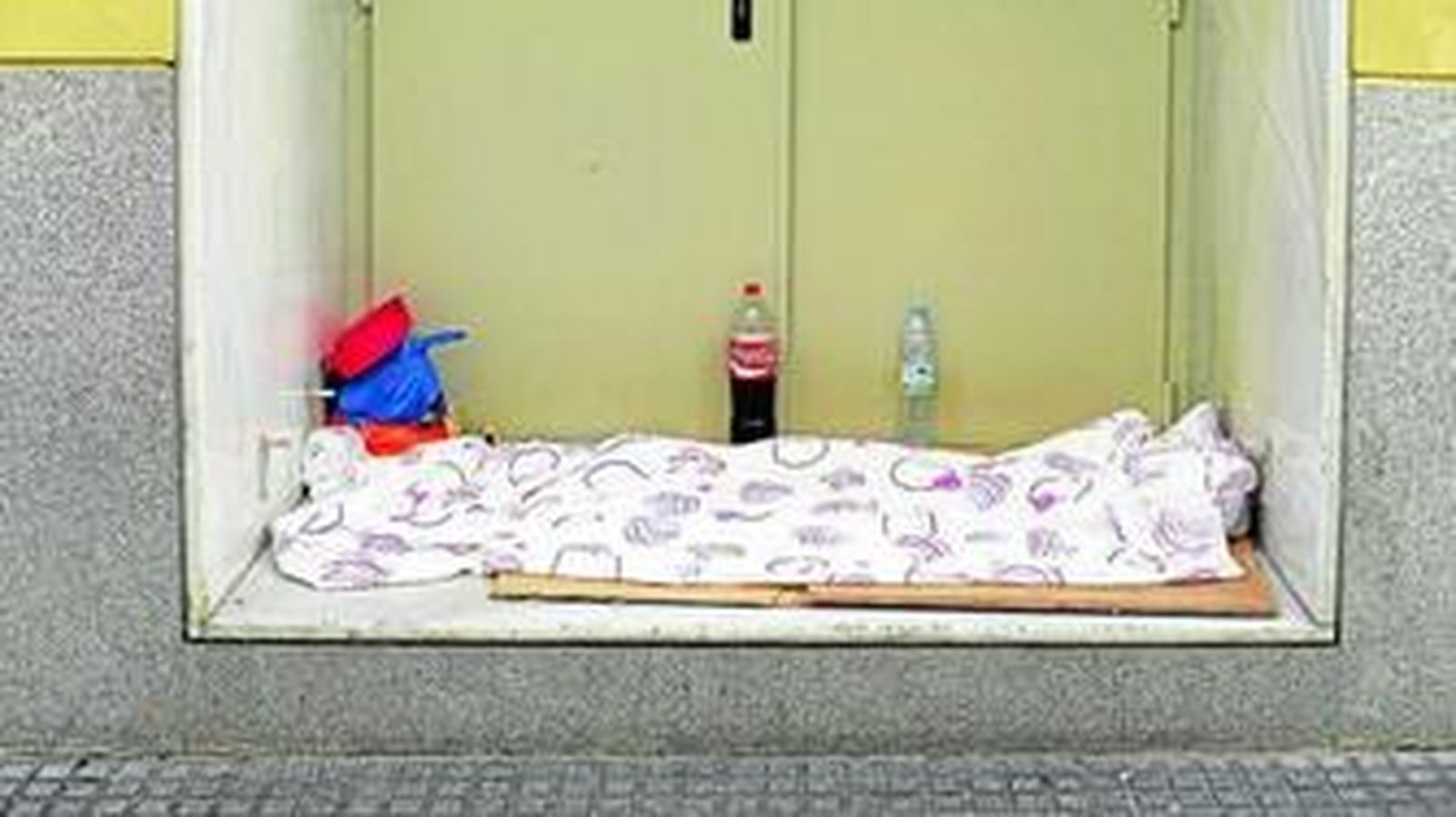 Lugar en el que duerme una persona sin hogar, en la puerta de emergencia de un establecimiento.