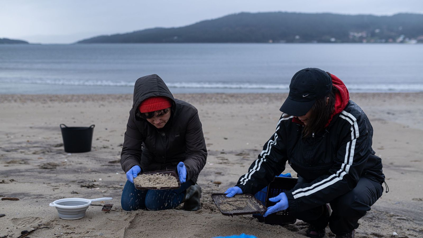 Dos voluntarios recogen pellets en la costa gallega