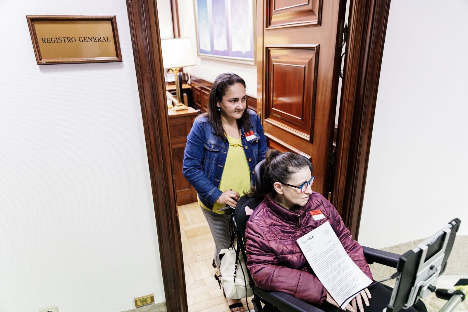 Una persona afectada de ELA sale tras registrar la petición de que se desbloquee la tramitación de la Ley ELA en el Congreso.