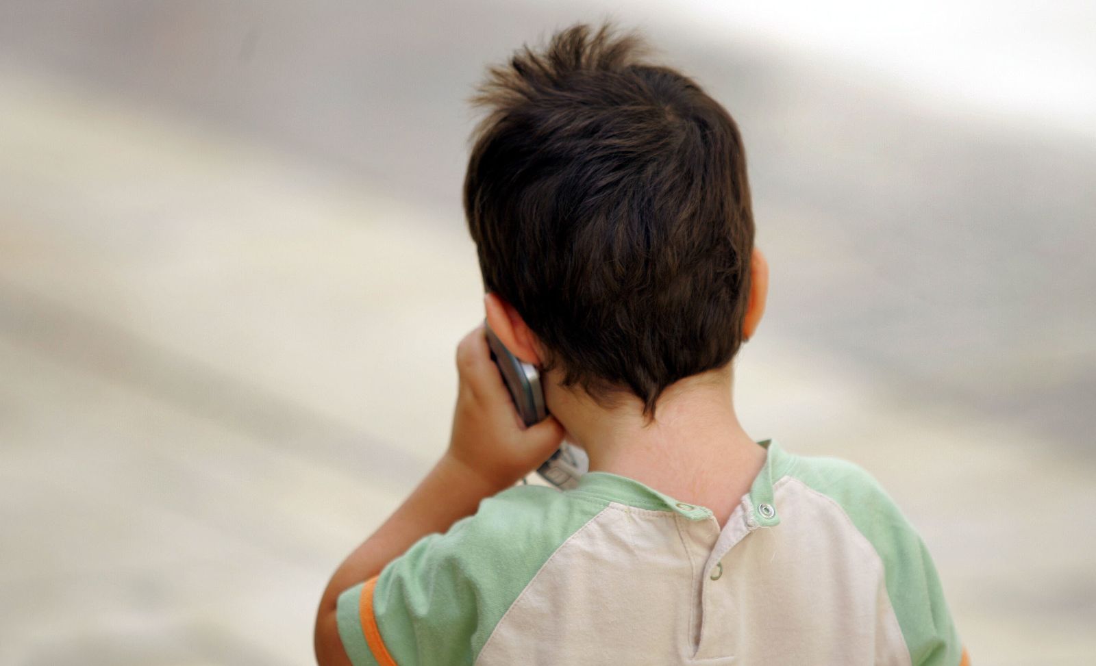 Un niño hablando por un teléfono móvil.