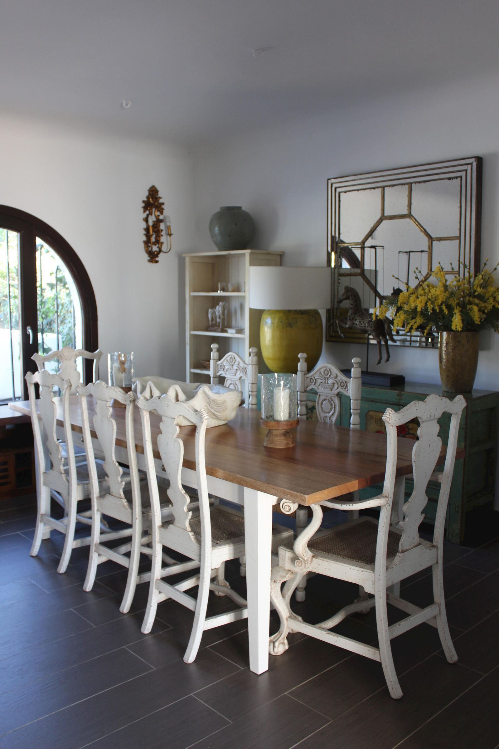 Mesa con tablero de madera natural y base decapada, junto con la sillas y sillones en el comedor.