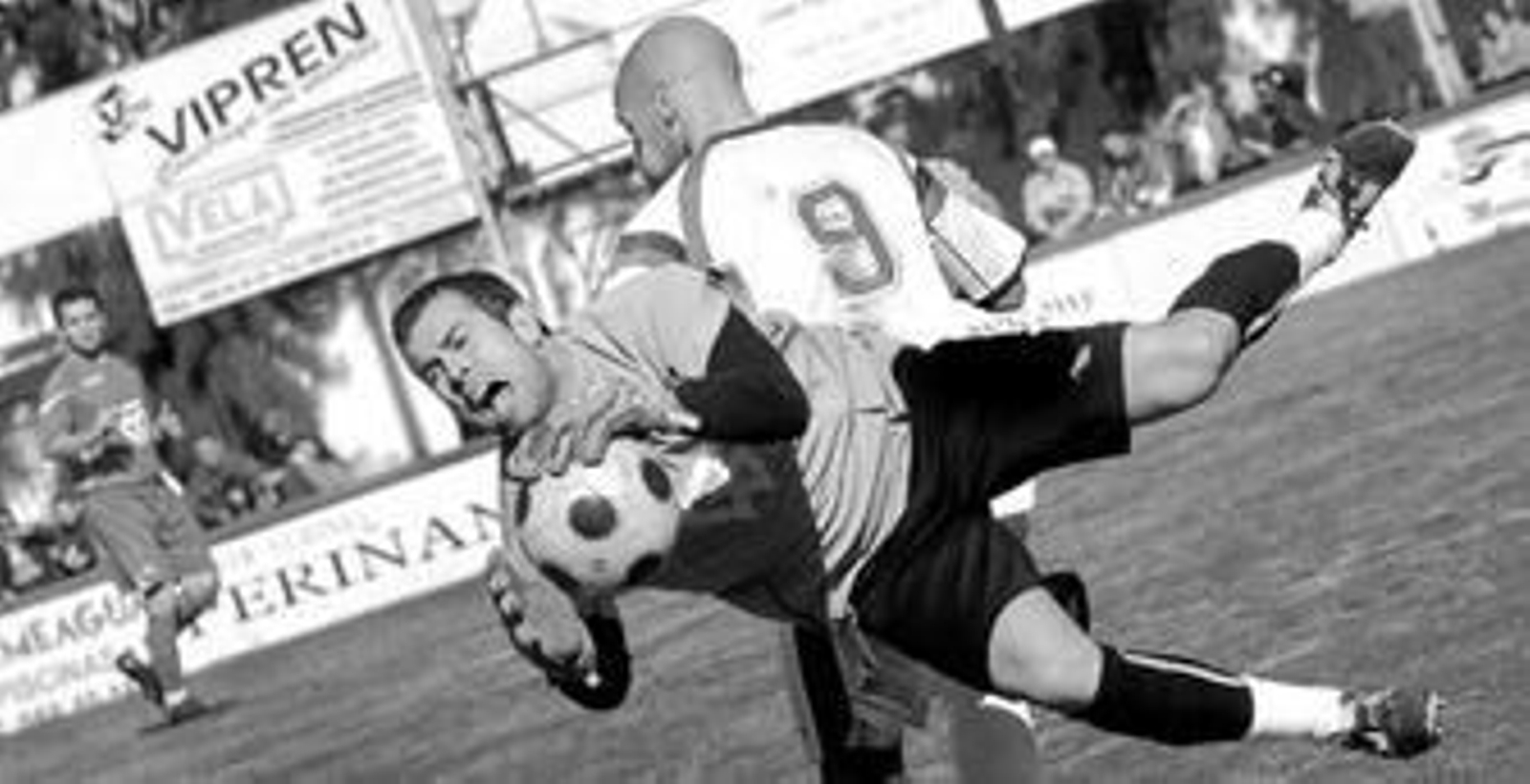 Miguel Díaz atrapa el esférico, obstaculizado por un adversario.