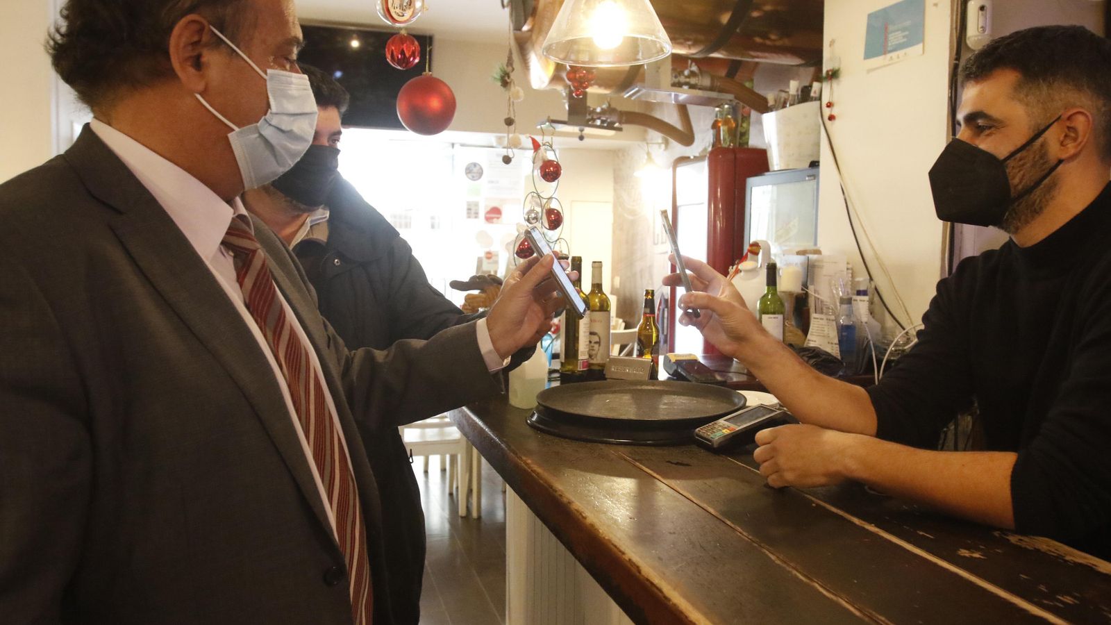 Un camarero le pide el certificado covid a un cliente en el interior del local